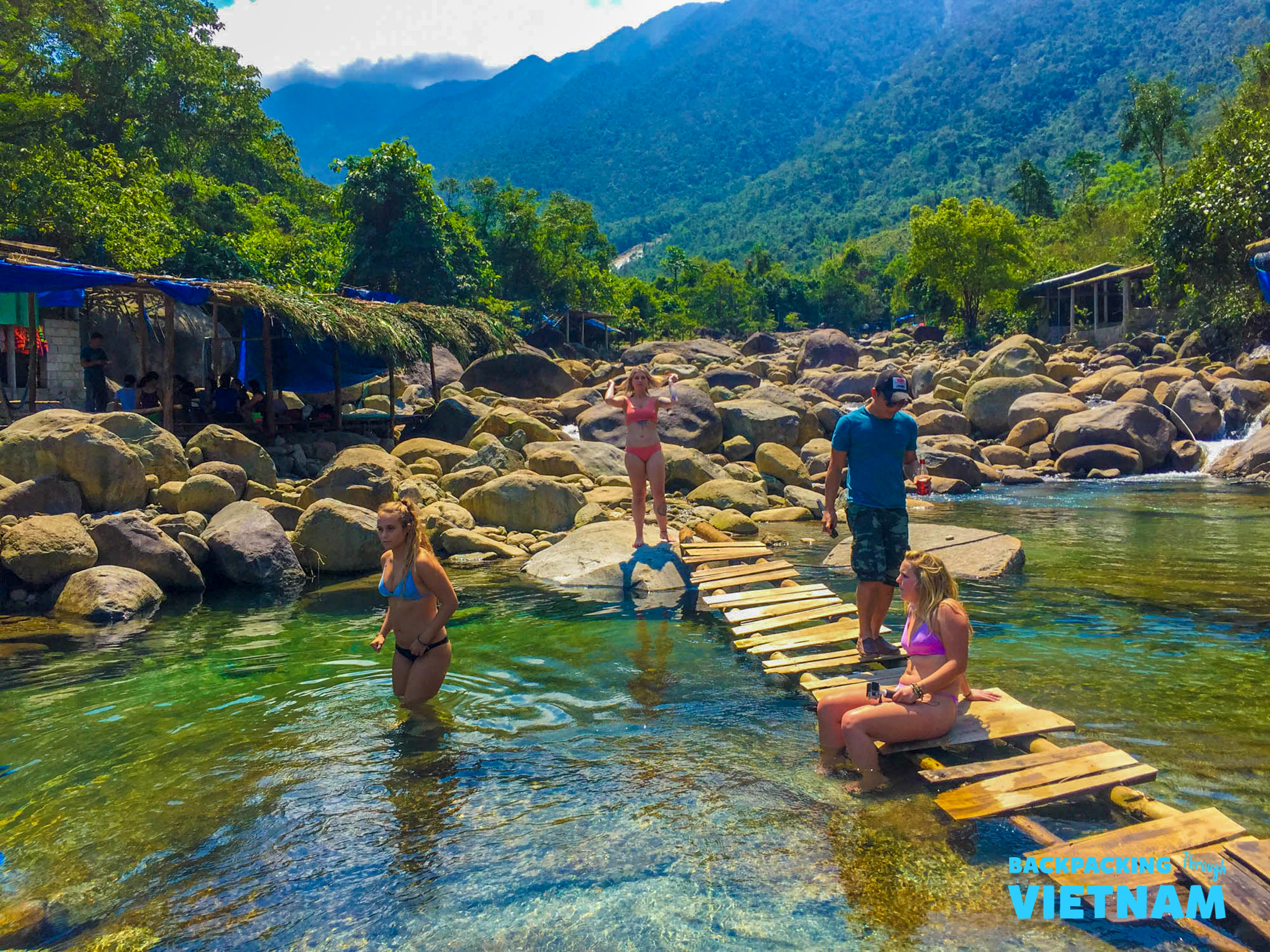 Four friends enjoy a refreshing swim in a clear mountain spring in Vietnam.