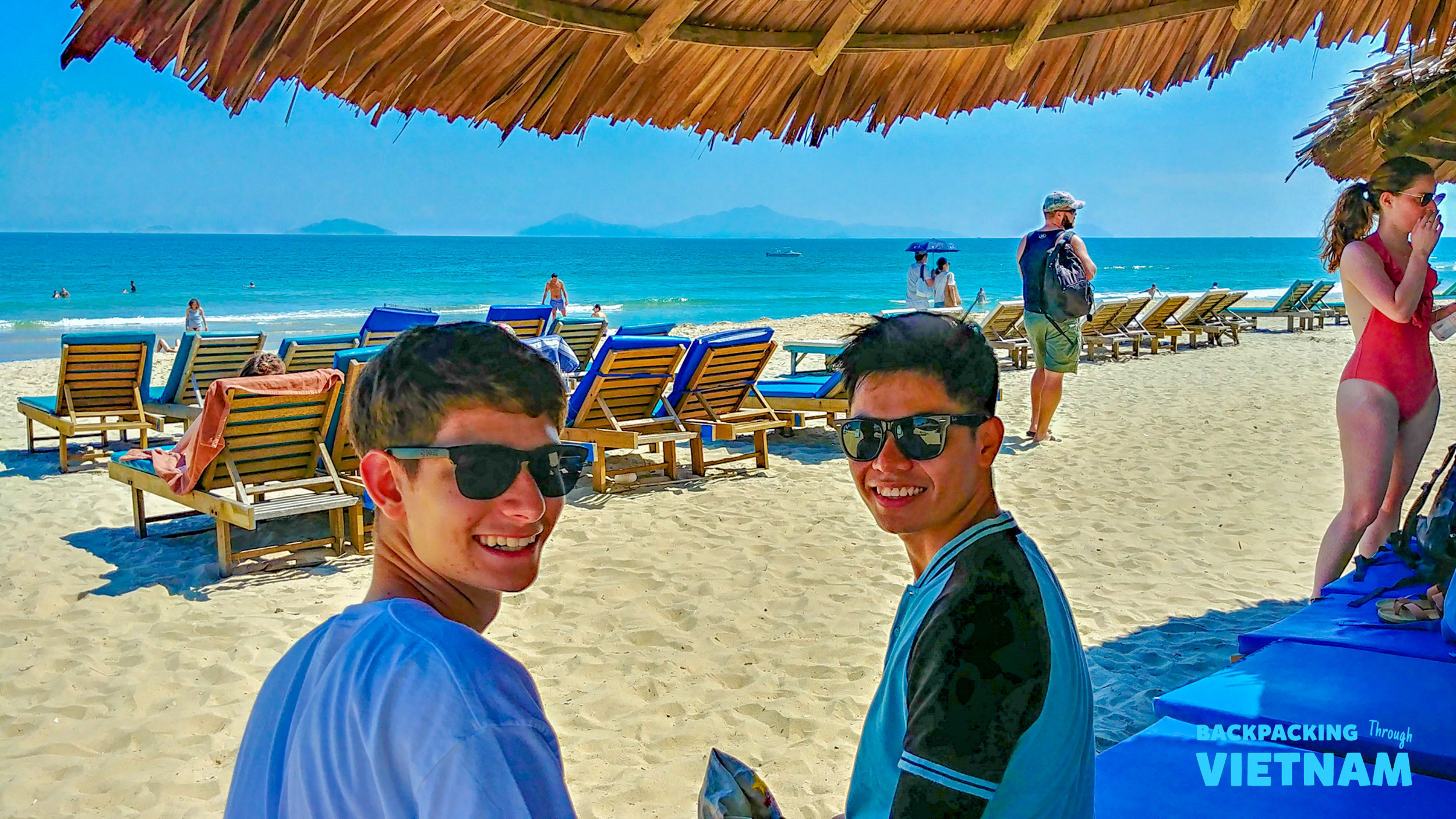 Happy backpackers enjoying the beautiful white sand beach and blue ocean in Hoi An.
