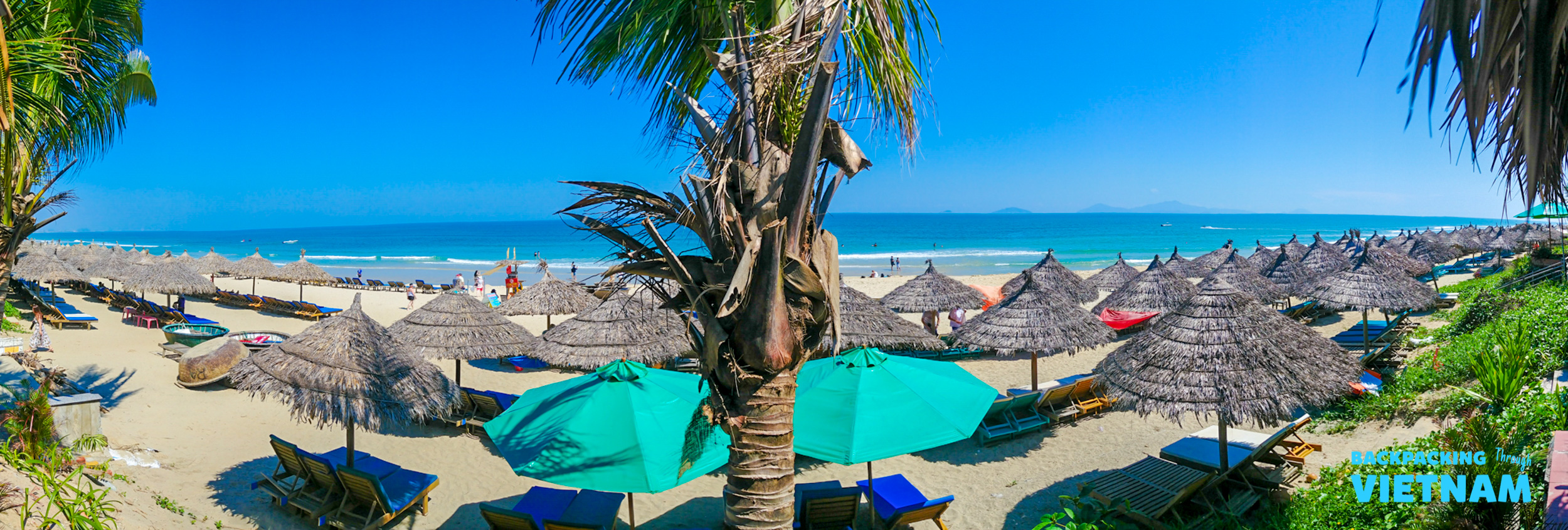 Numerous straw umbrellas and lounge chairs line the white sands of An Bang Beach in Hoi An.