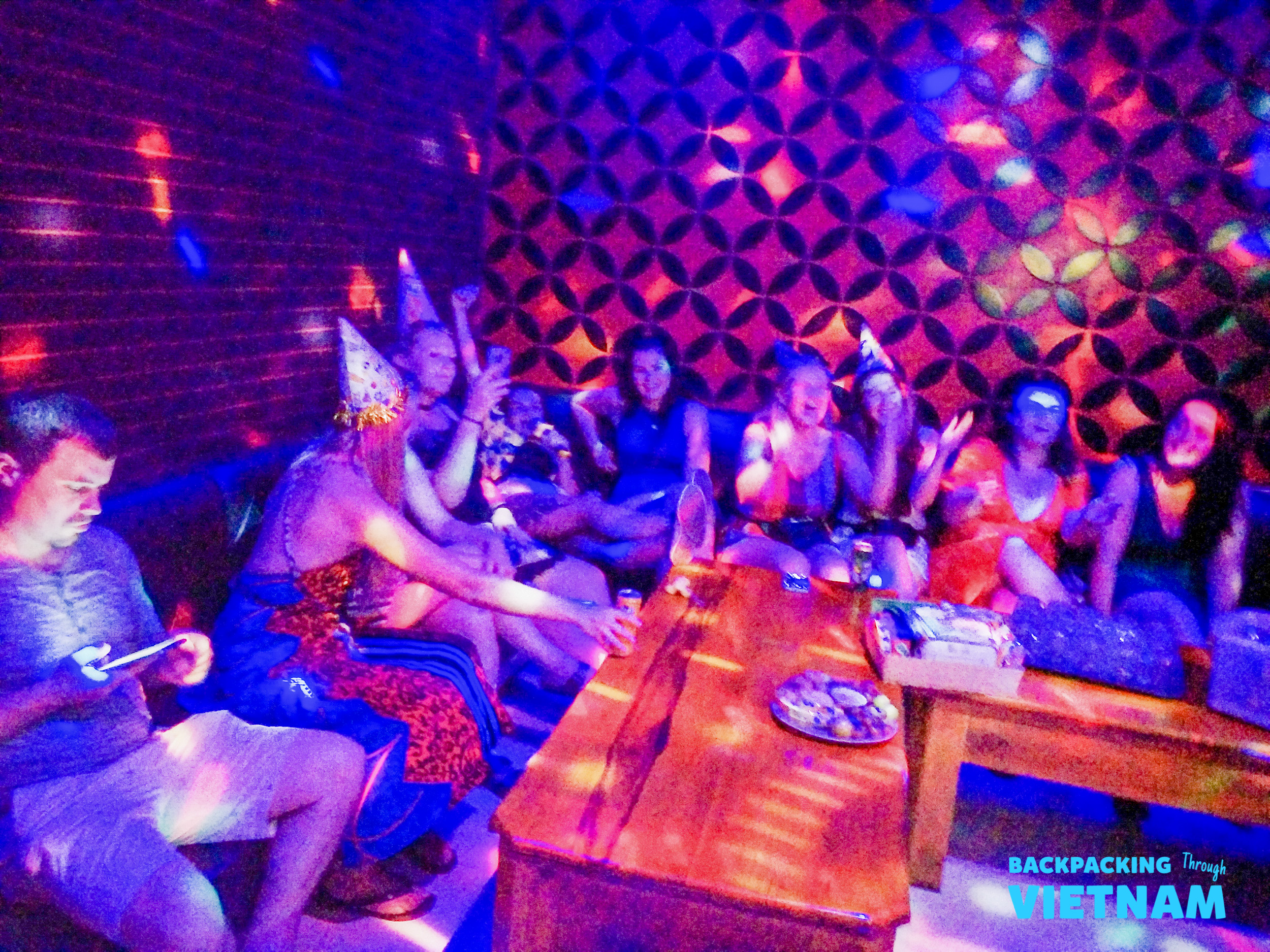 A group of happy backpackers celebrating with party hats under vibrant disco lights.