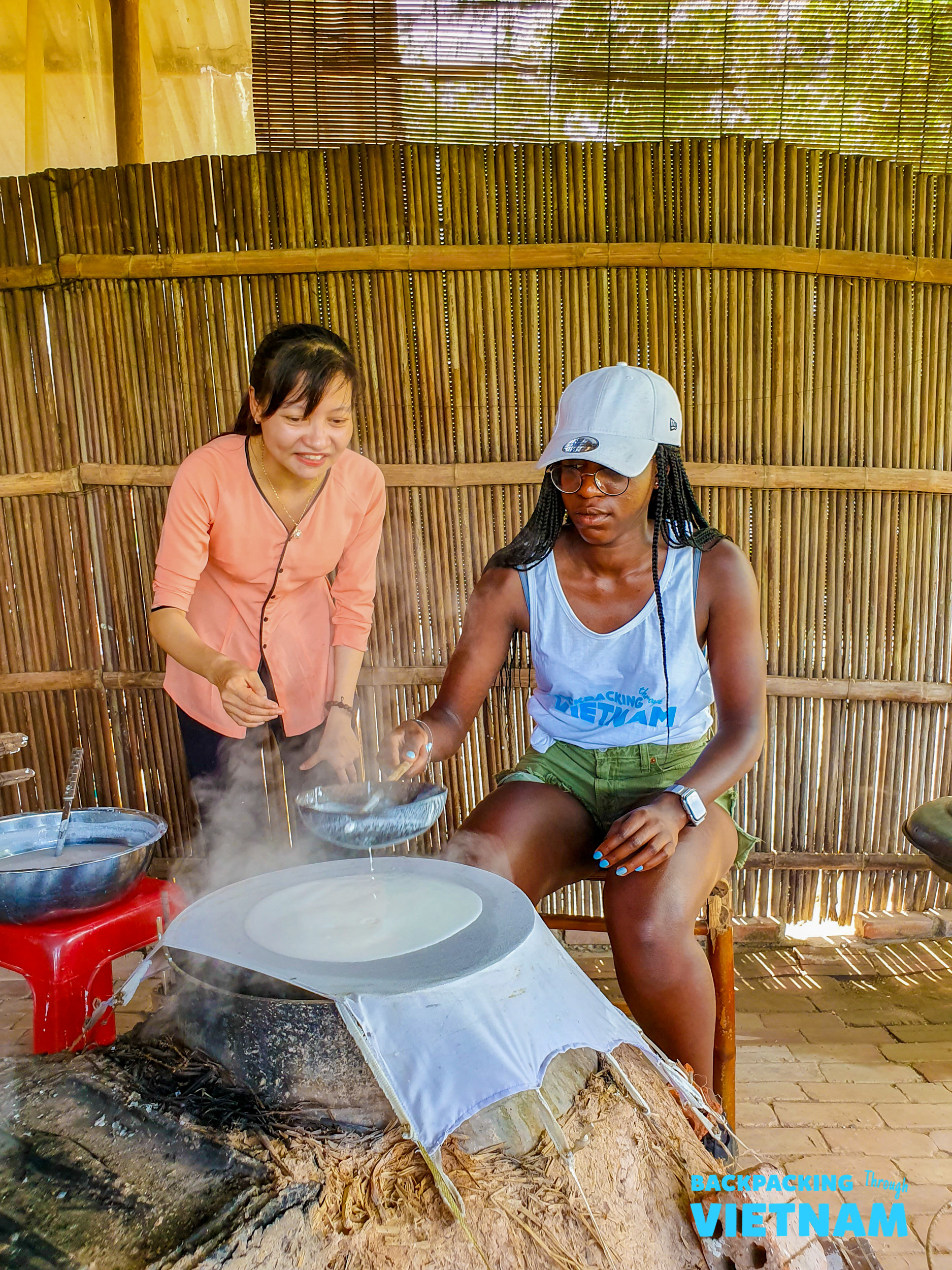 A traveler learns to make traditional Vietnamese rice paper with a local woman in Hoi An.