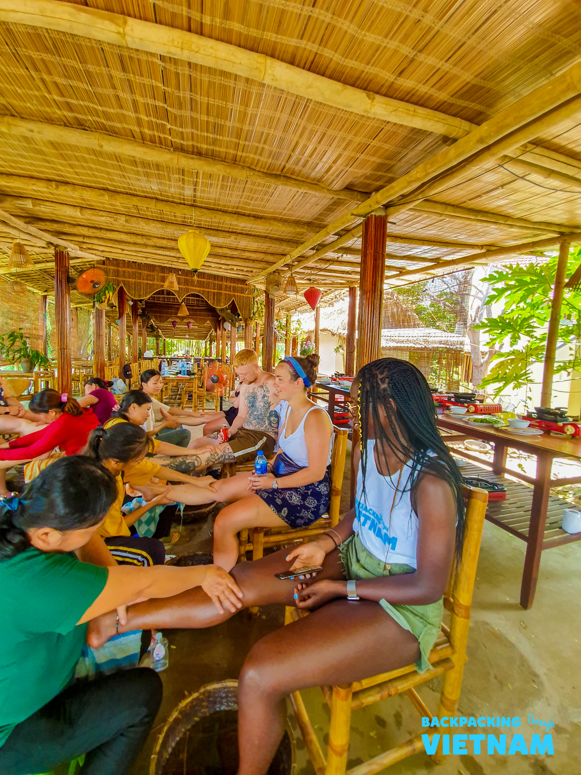 Tourists enjoy relaxing foot massages in a traditional bamboo hut in Hoi An, Vietnam.