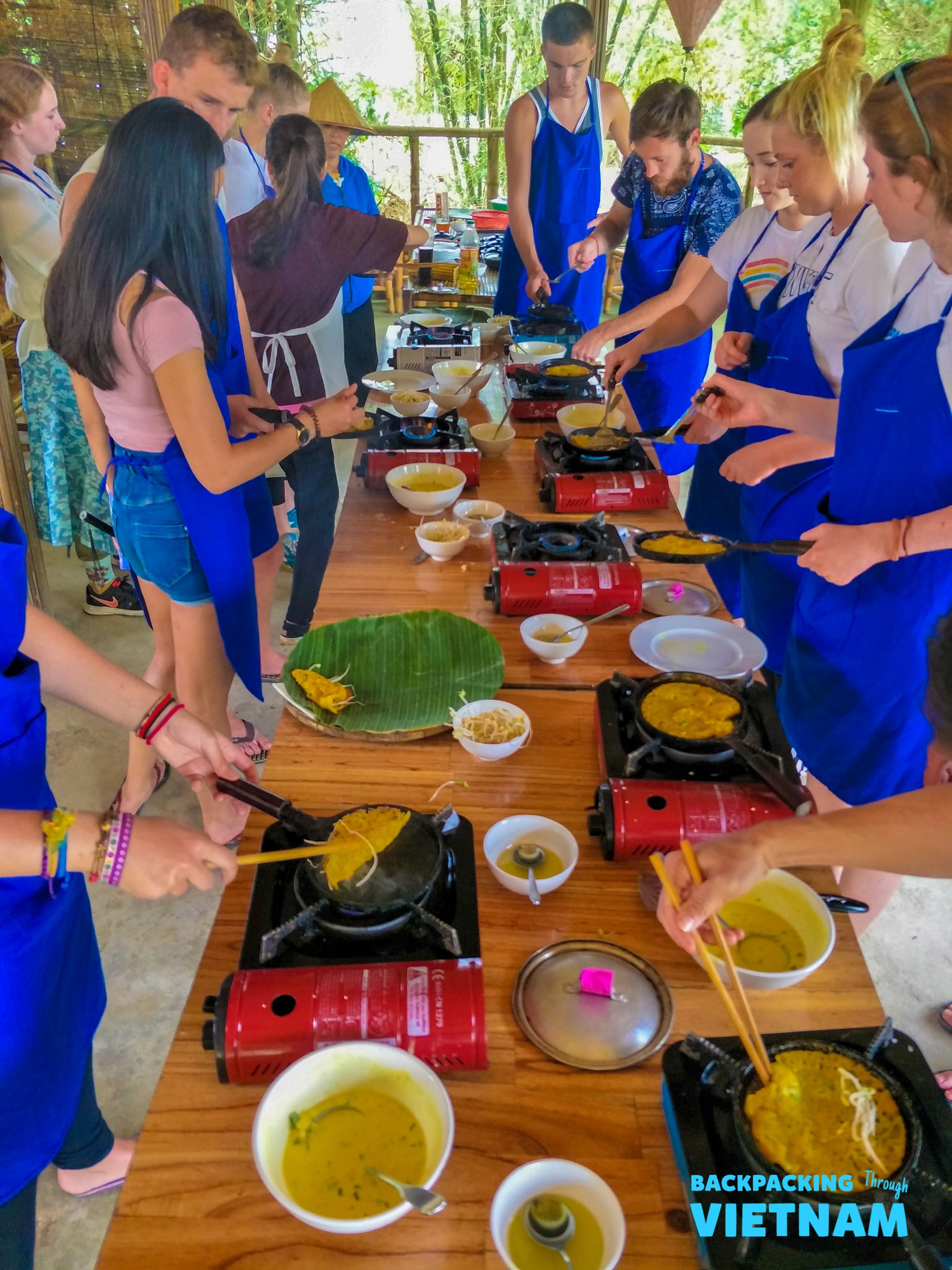 Backpackers enthusiastically prepare Vietnamese dishes during a cooking class at an organic farm in Hoi An.