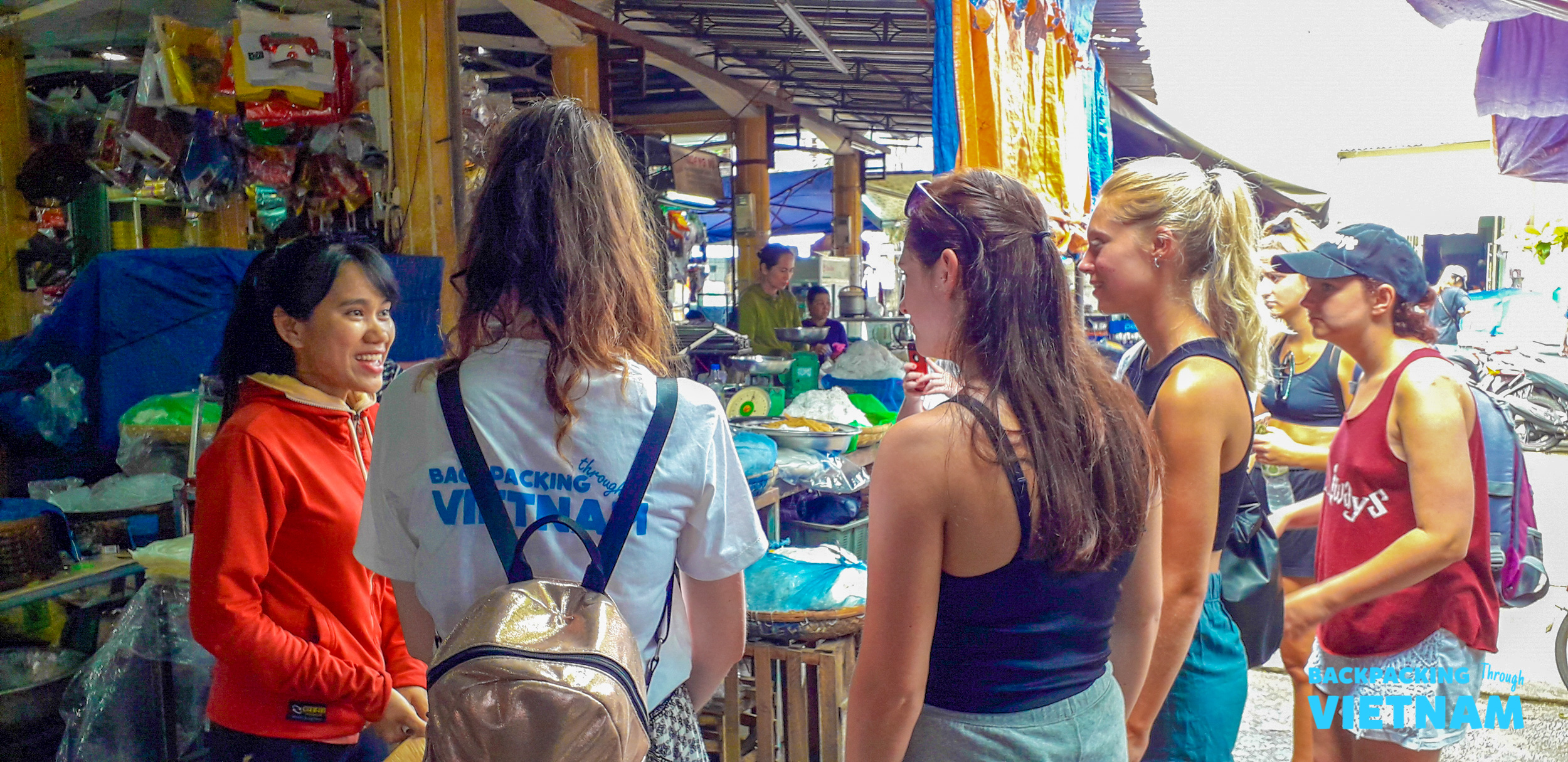 Tourists engaging with a local vendor at a vibrant market in Hoi An, Vietnam.