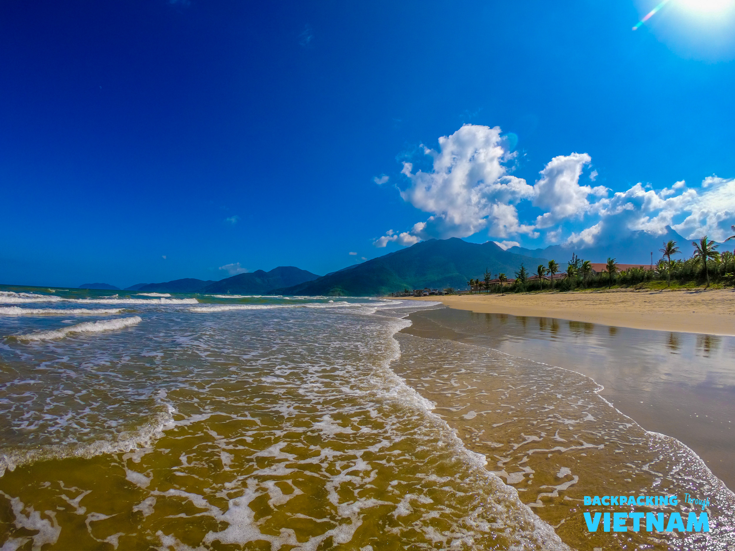 The beautiful coastline of Nha Trang, Vietnam, with golden sand, gentle waves, and distant green mountains.