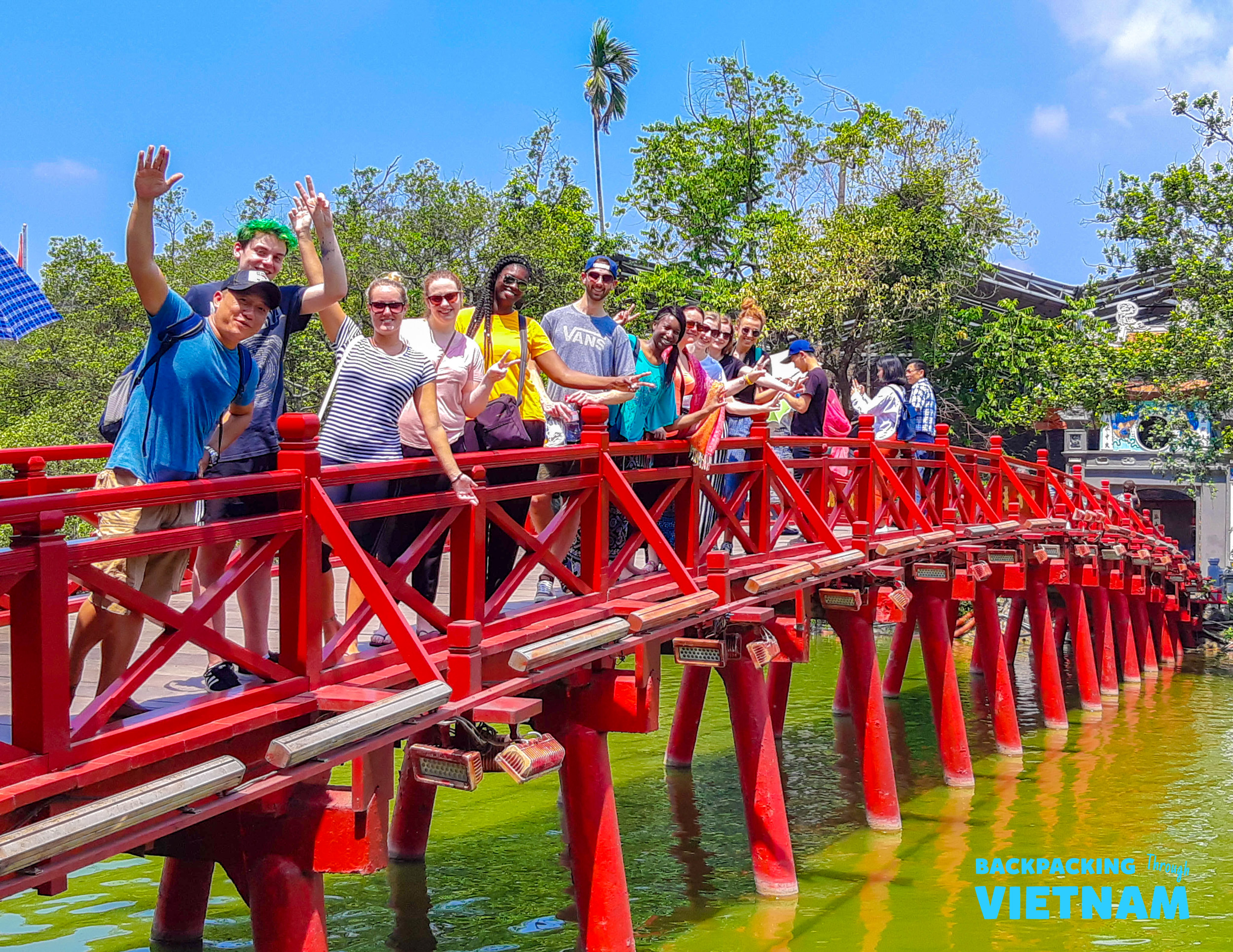 Backpacking group crossing red Huc Bridge at Hoan Kiem Lake