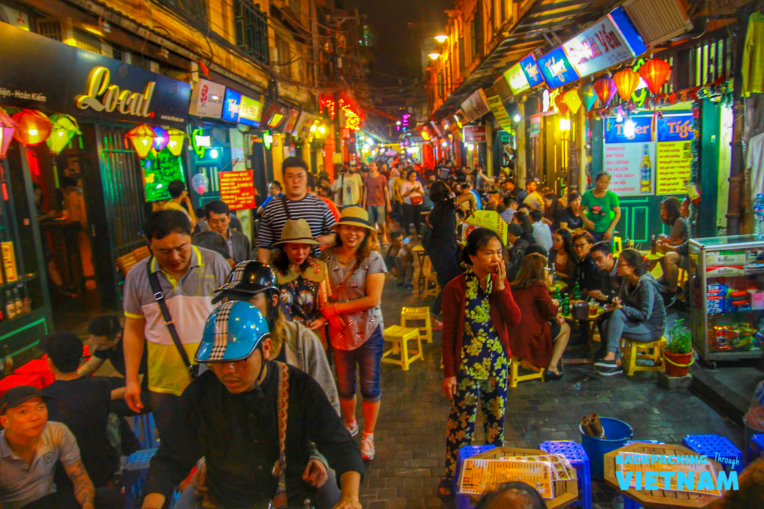A bustling night street in Hanoi, Vietnam, filled with people enjoying the vibrant atmosphere.