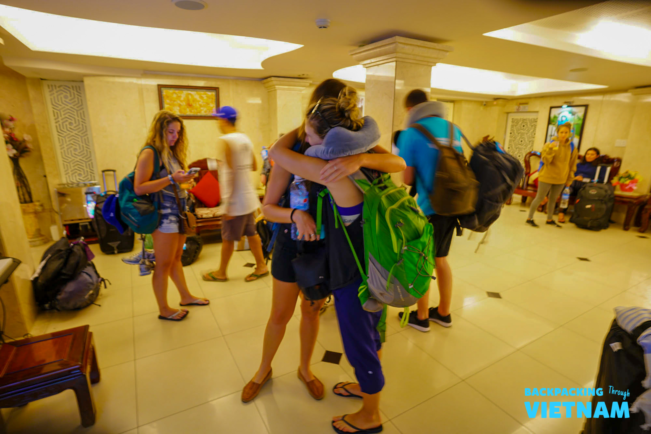 Backpackers hug goodbye in a hotel lobby in Hoi An, marking the end of their adventure.