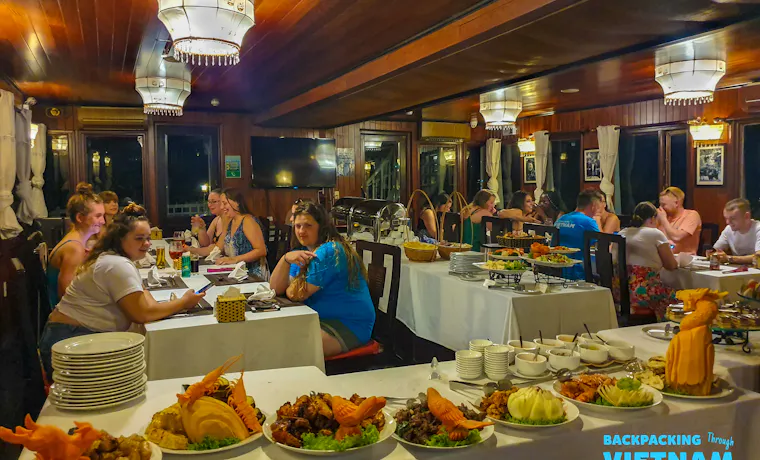 Travelers enjoy a delicious buffet dinner inside a sleeper boat while cruising Halong Bay, Vietnam.