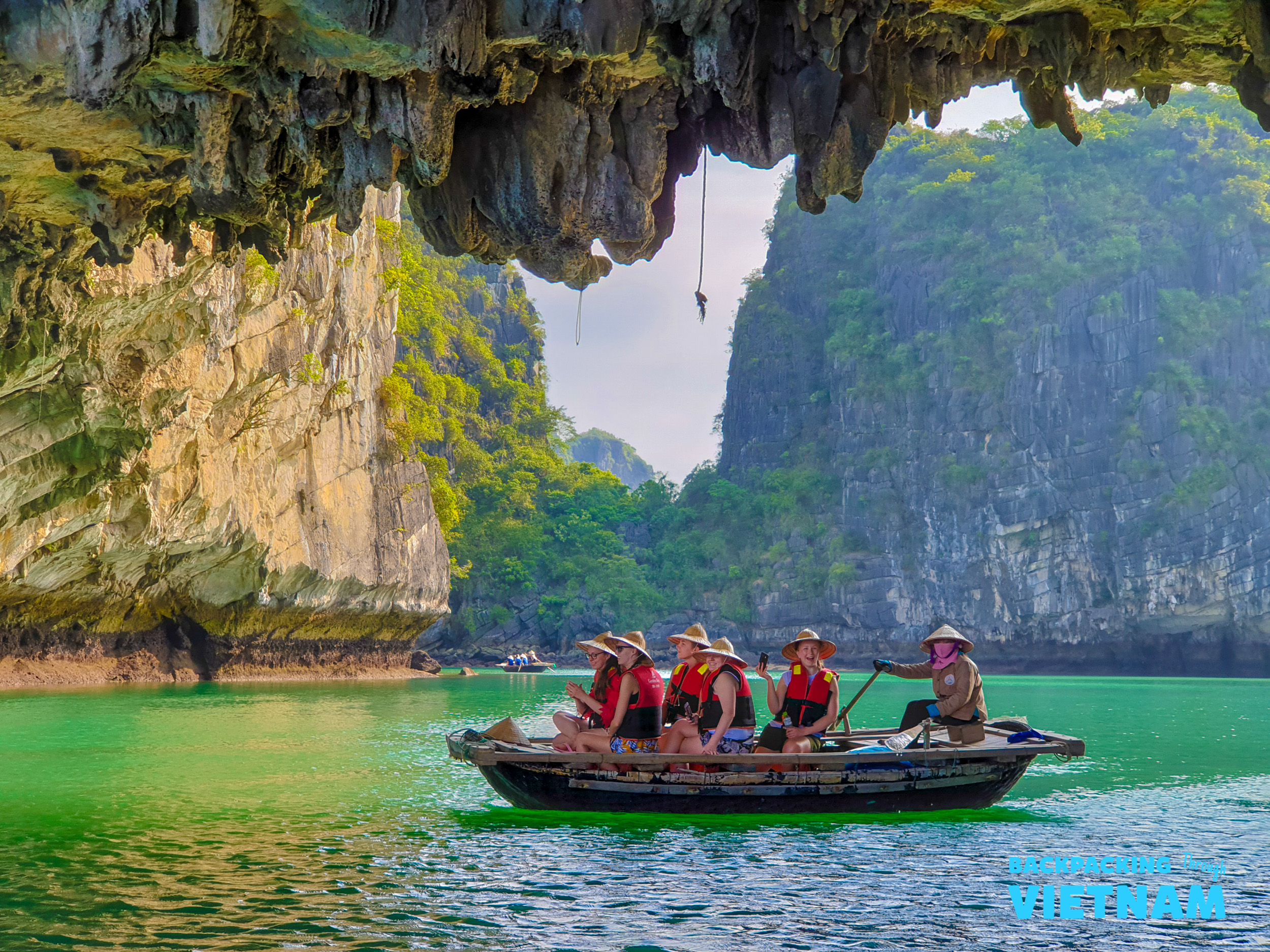 Tourists in a small boat explore a grotto with stunning limestone karsts in Tam Coc, Vietnam.
