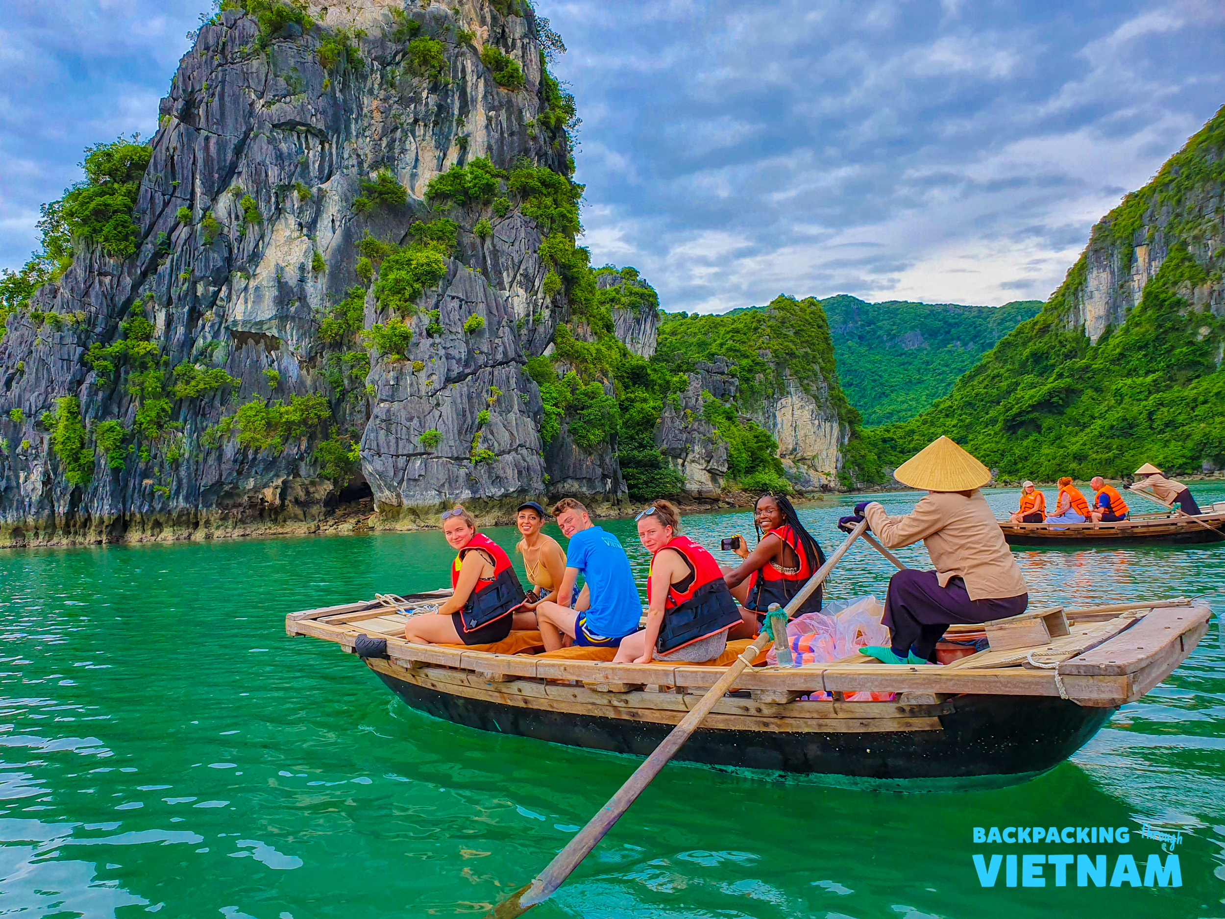 Friends in a traditional boat explore the emerald waters and towering limestone karsts of Tam Coc.