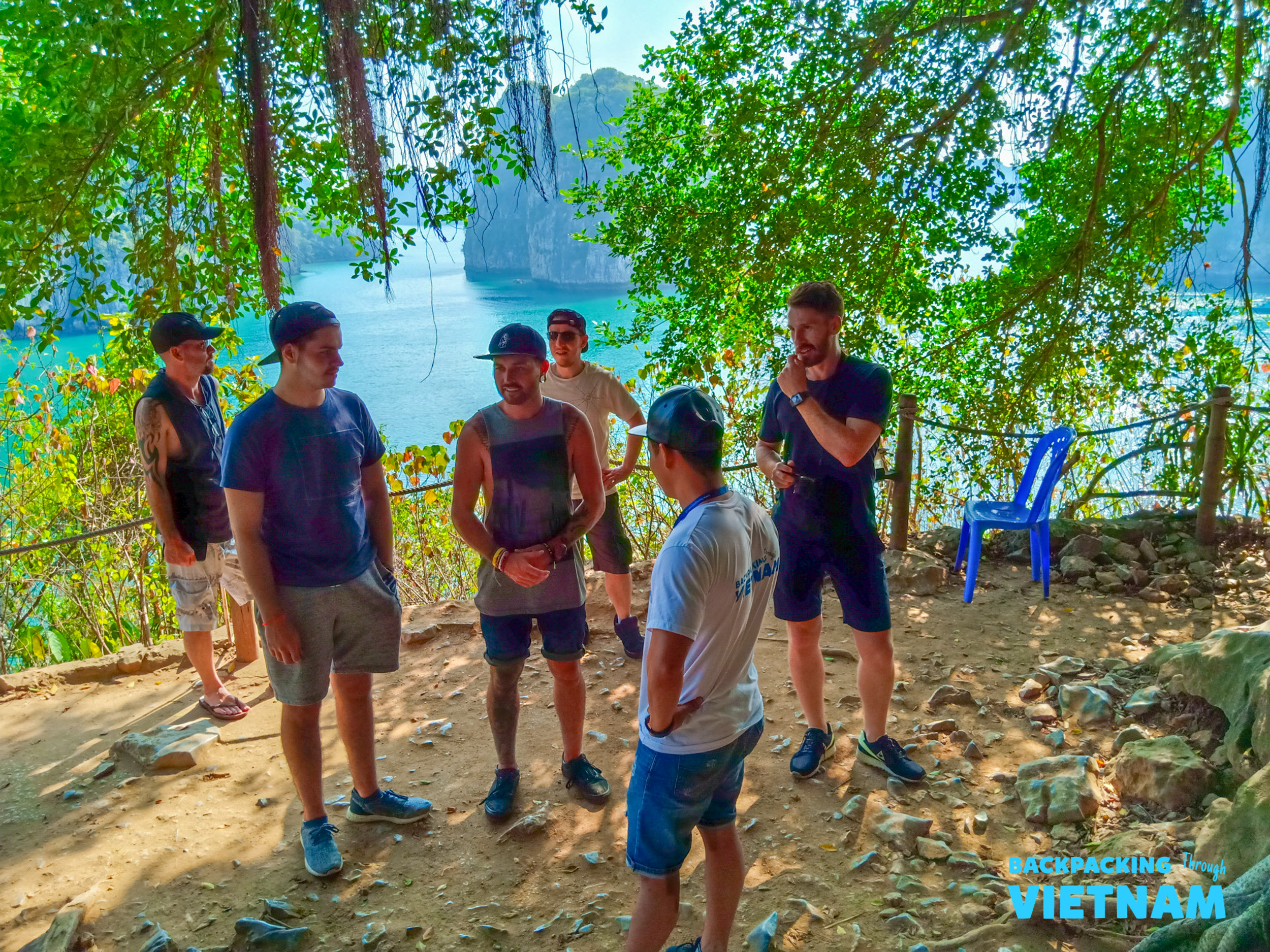 Backpackers gather under trees, overlooking the beautiful limestone islands of Vietnam's Halong Bay.