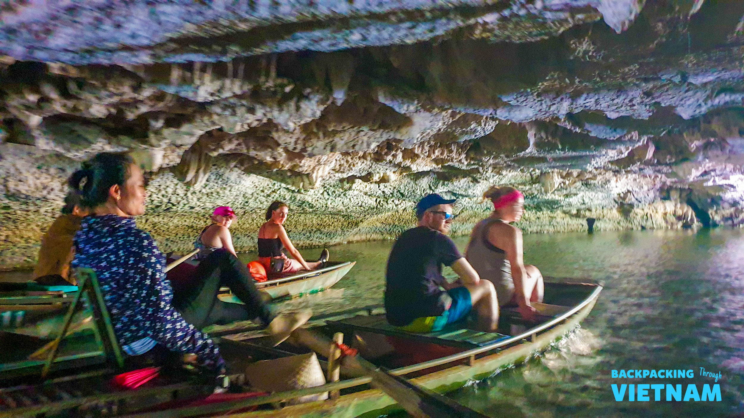 Travelers enjoy a peaceful boat ride through a magnificent illuminated cave in Tam Coc.