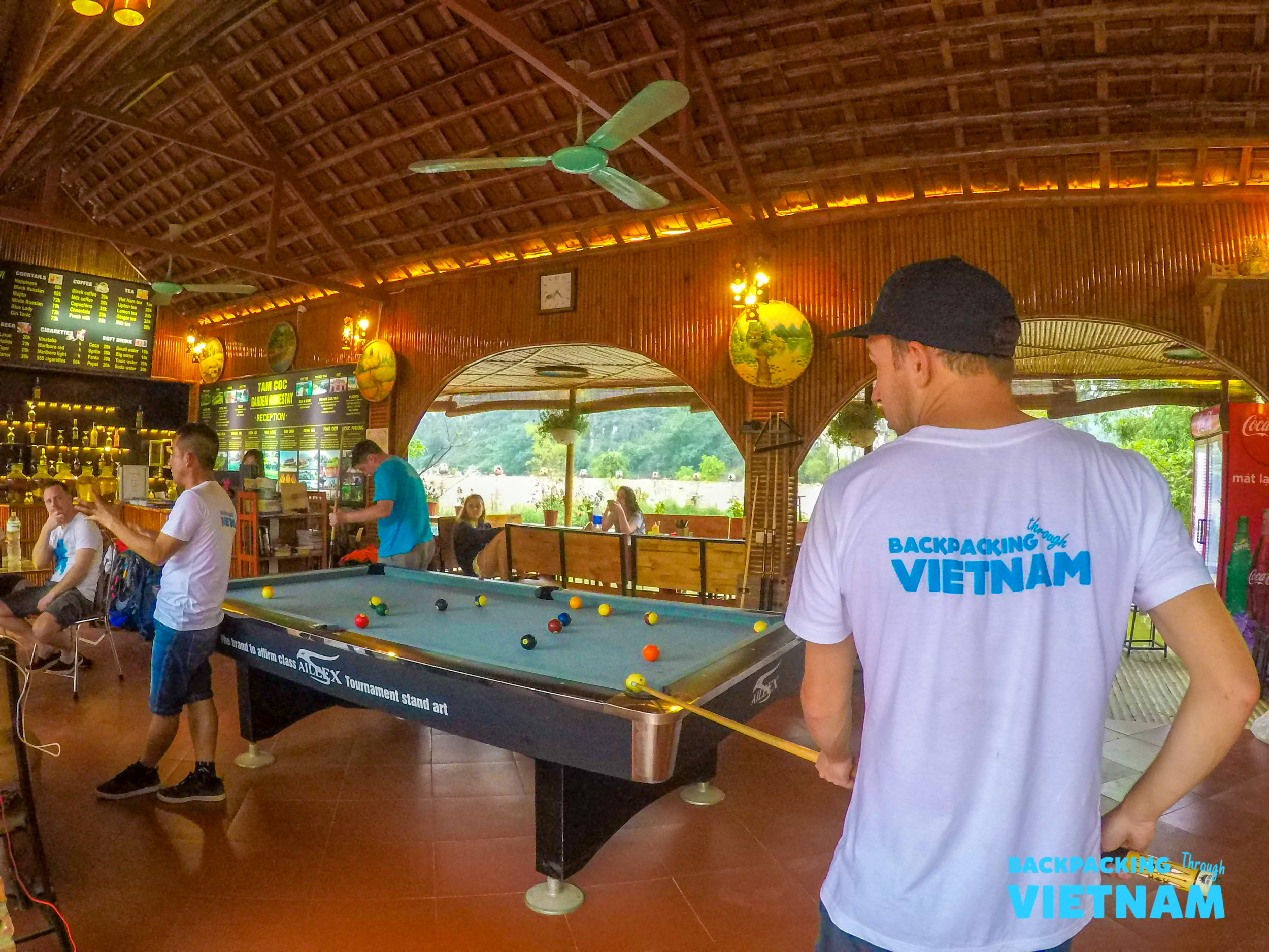 Backpacking Vietnam travelers enjoy a friendly game of pool at a rustic bar in Tam Coc.