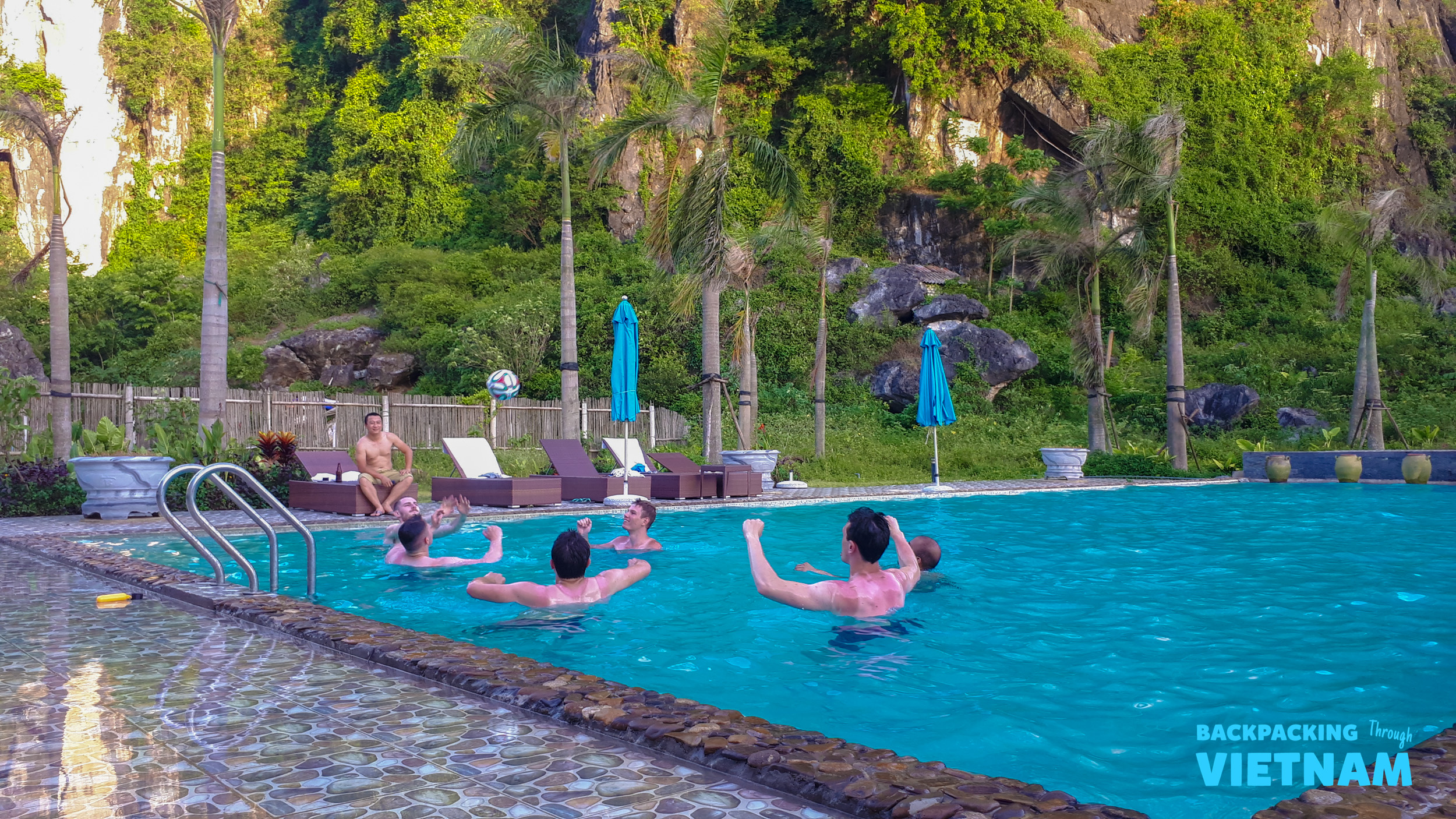 Friends enjoy a refreshing swim and play in a hotel pool surrounded by karst mountains in Phong Nha.