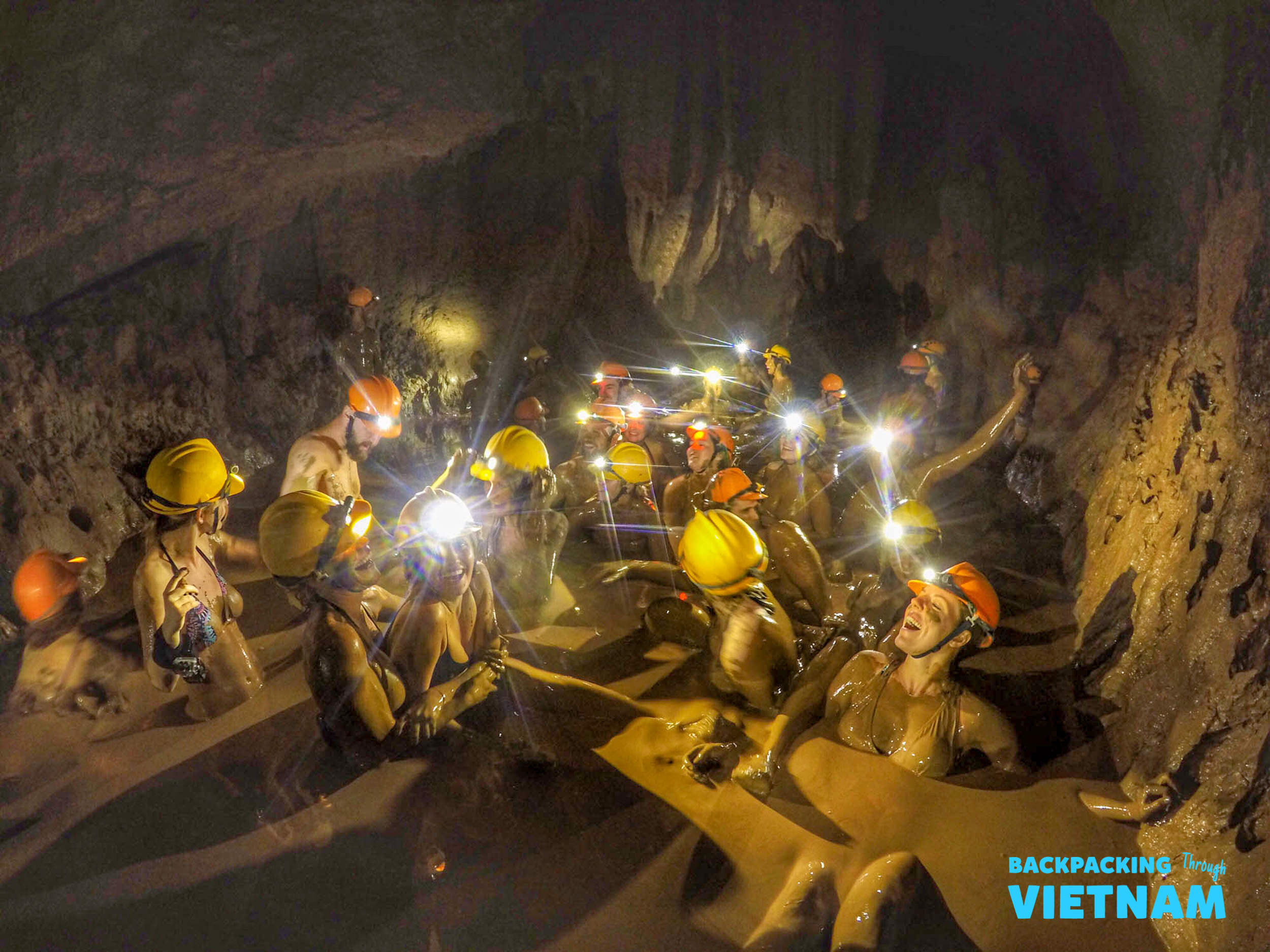 Happy backpackers covered in mud during an exciting Dark Cave caving experience in Phong Nha, Vietnam.