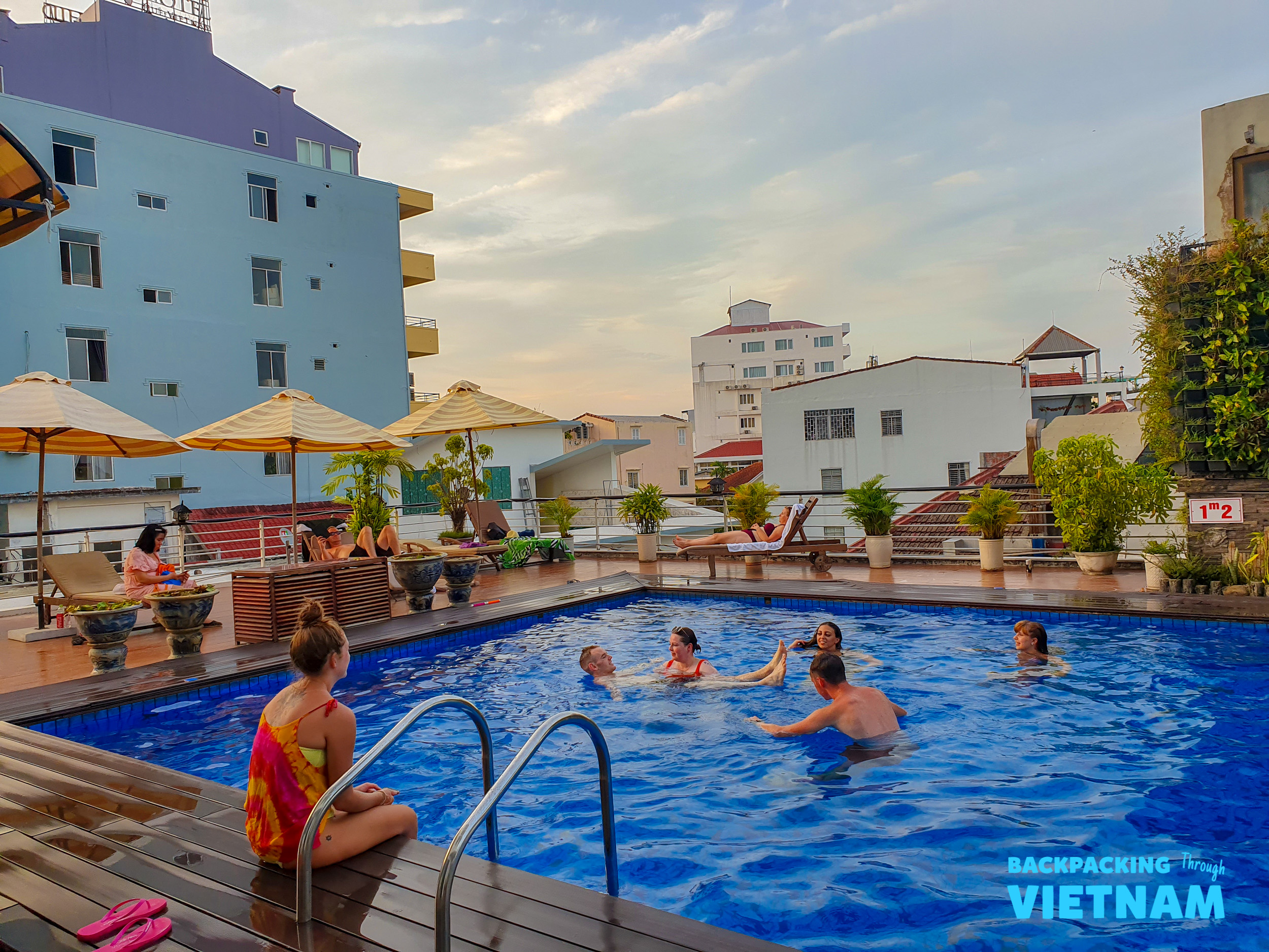 Friends relax and swim in a rooftop pool overlooking the city of Hue, Vietnam.