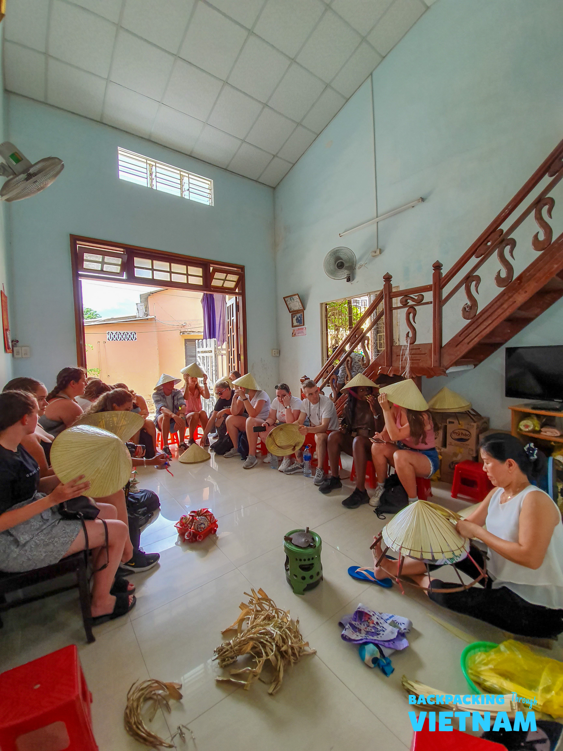 Tourists learn to make traditional Vietnamese conical hats with a local artisan in Hue.