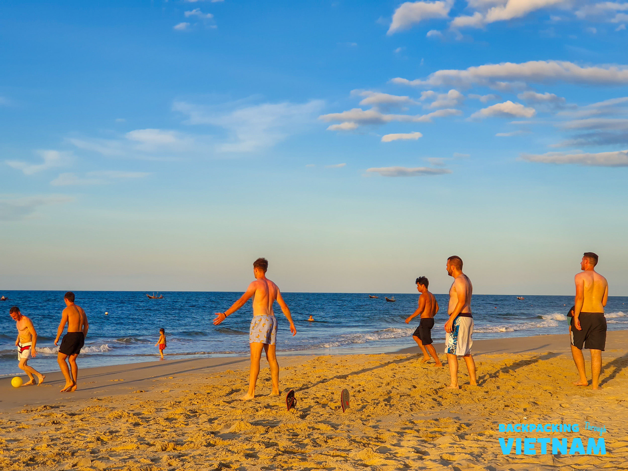 Backpackers enjoy a spirited game of beach soccer on a sunny afternoon near Hue, Vietnam.