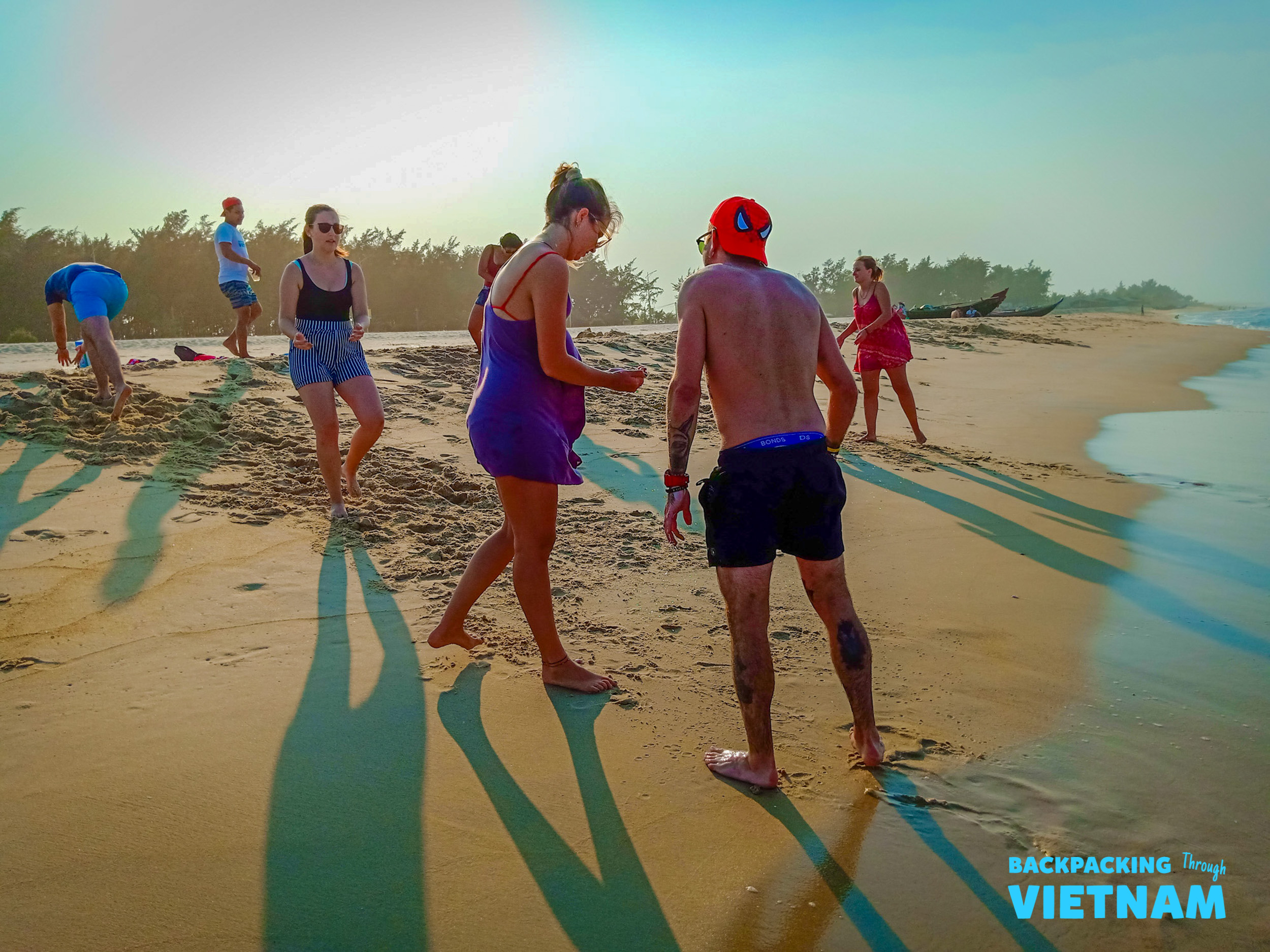 Backpackers enjoy a relaxing beach stop in Vietnam, playing in the sand under the warm sun.