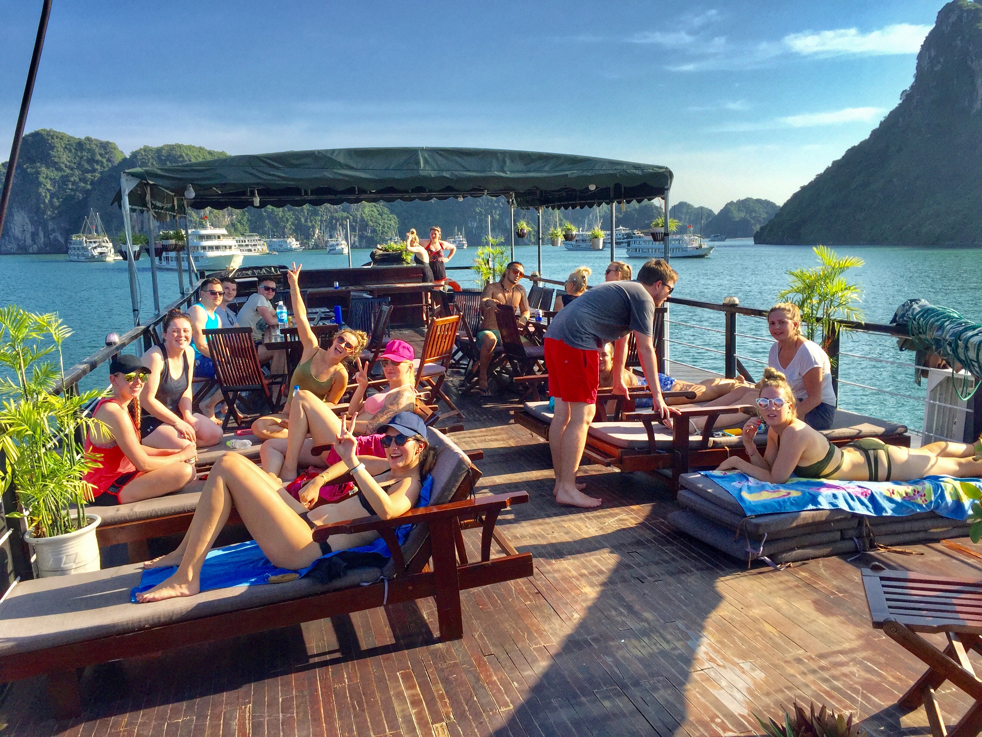 Happy backpackers relax and sunbathe on a boat deck in sunny Halong Bay, Vietnam.