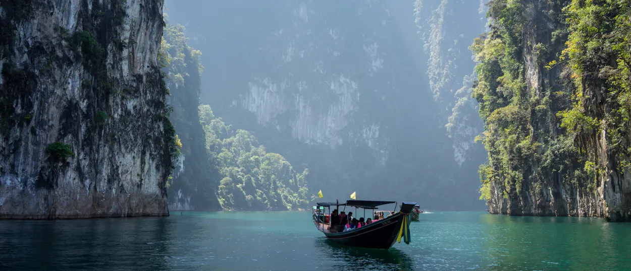 A longtail boat carries tourists through the stunning limestone karsts and clear waters of Khao Sok.