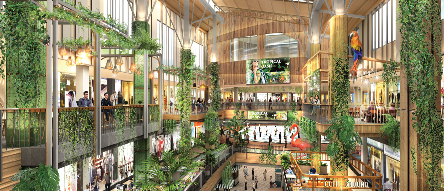 A vibrant multi-story shopping mall in Phuket, filled with people, lush green plants, and unique animal sculptures.