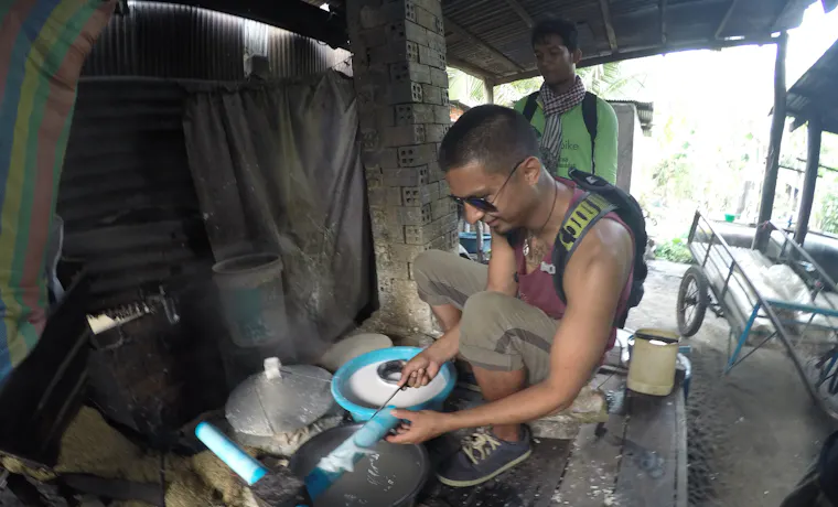 Justin Molina processes a white substance with blue tubes in a rustic Cambodian workshop.