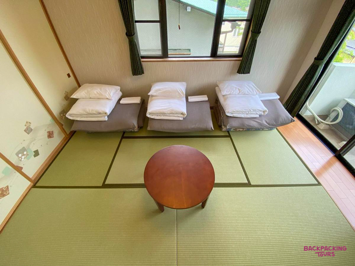 Traditional Japanese guesthouse room in Hakone with three futon beds on tatami mats.