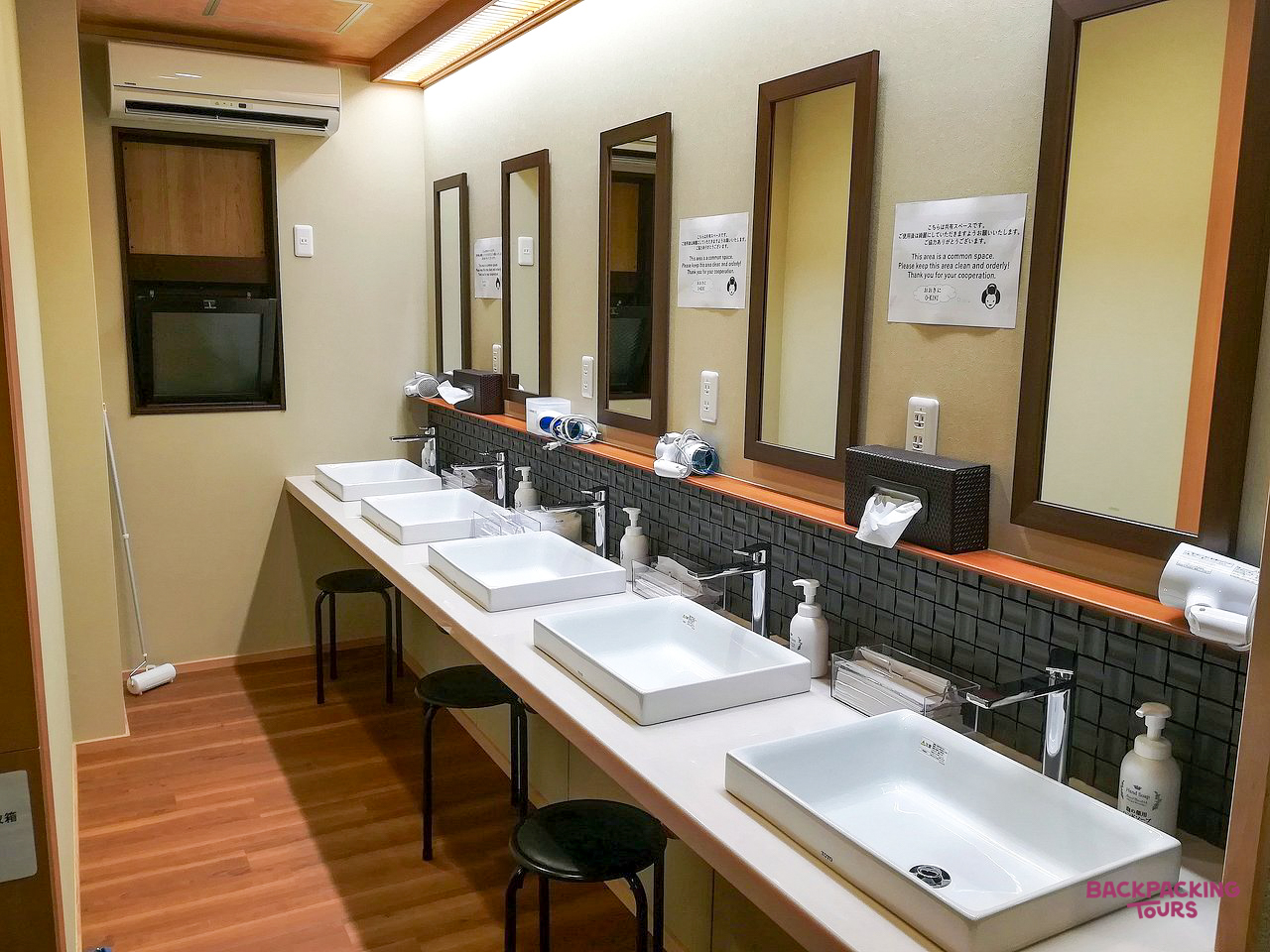 A row of modern sinks and mirrors in a shared washroom at a ryokan hostel in Kyoto.
