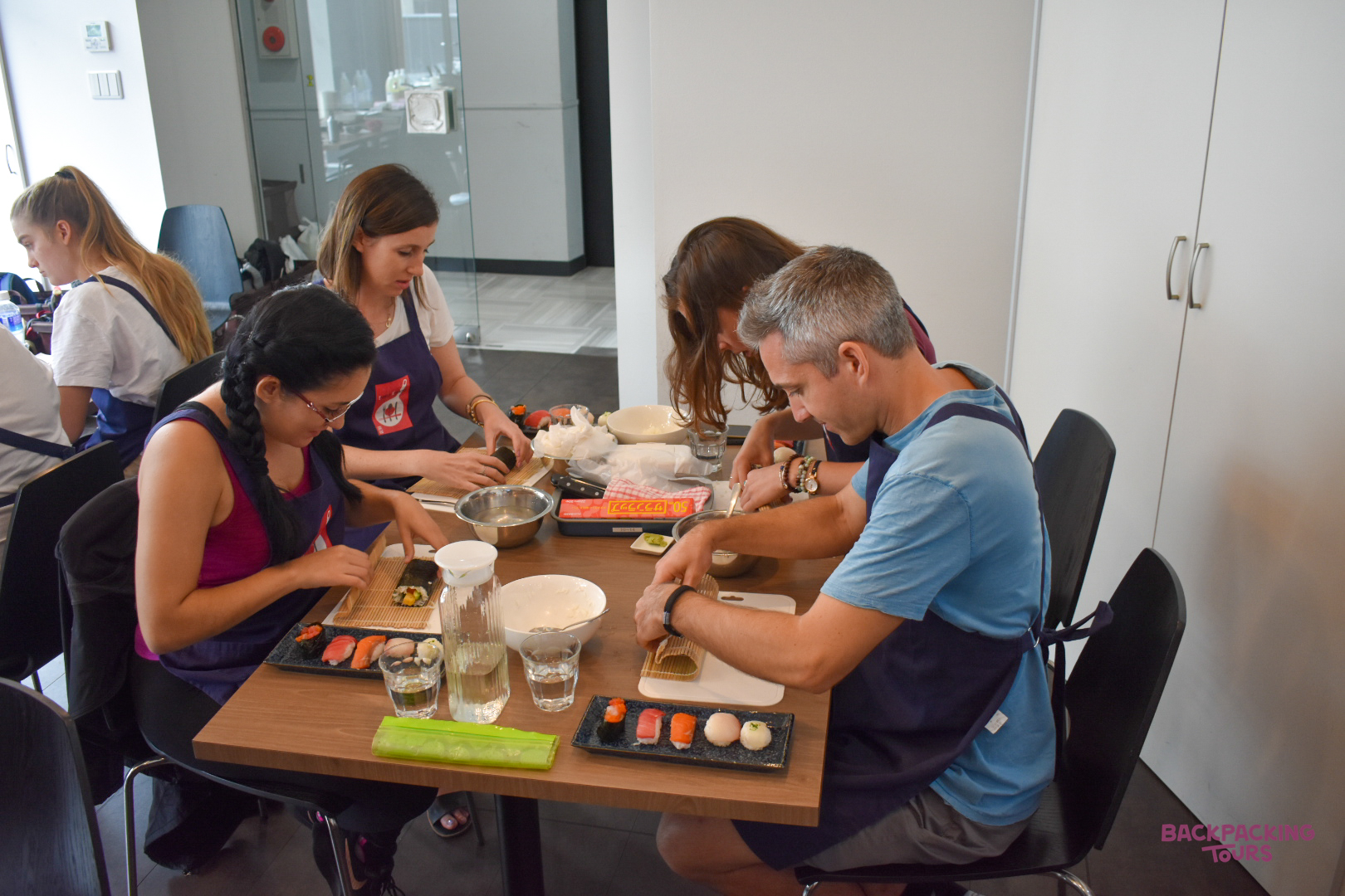 A group of backpackers enjoying a hands-on sushi making class in Tokyo, Japan.