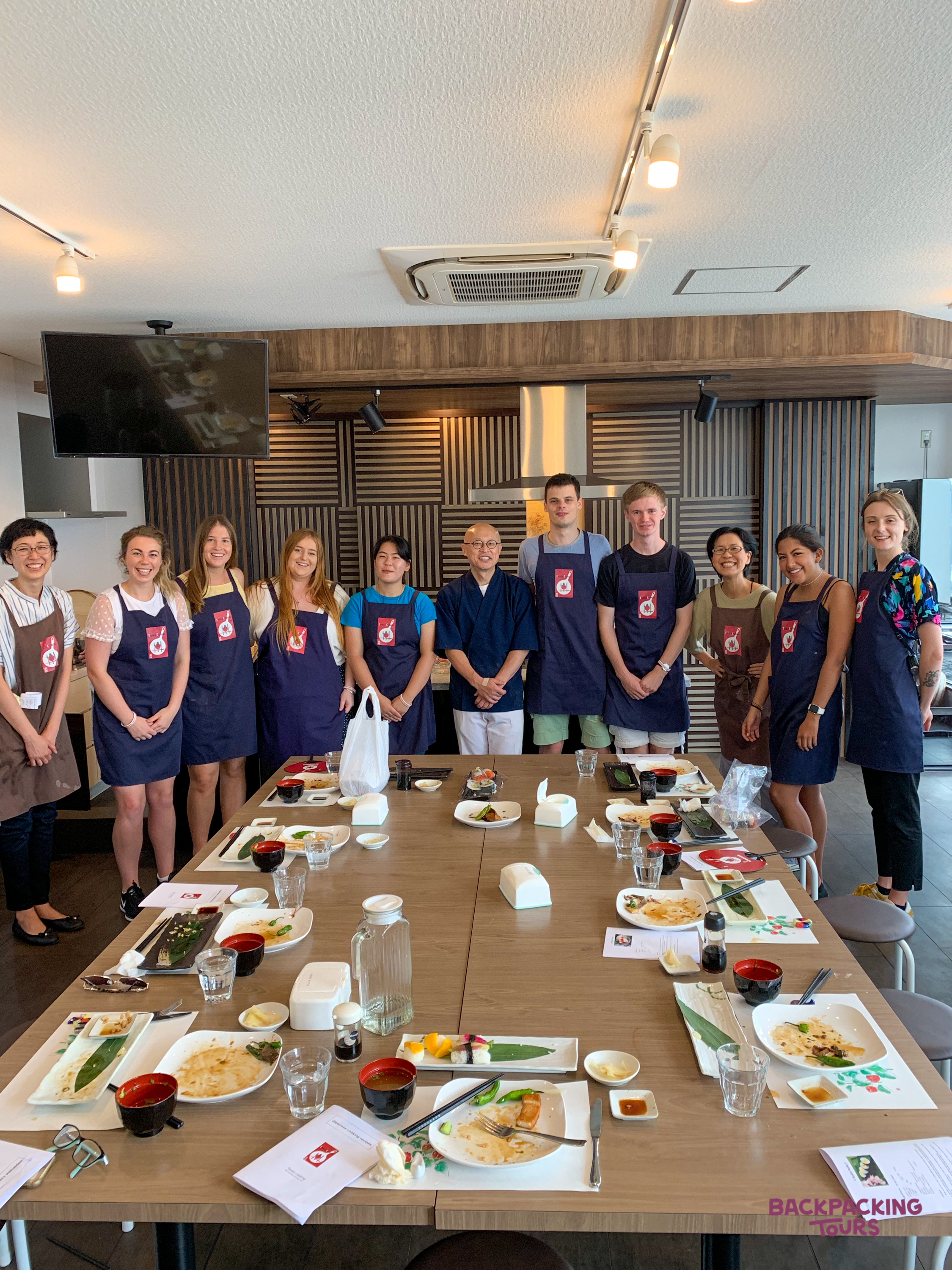 Happy group of travelers and instructors after a fun sushi making class in Tokyo.