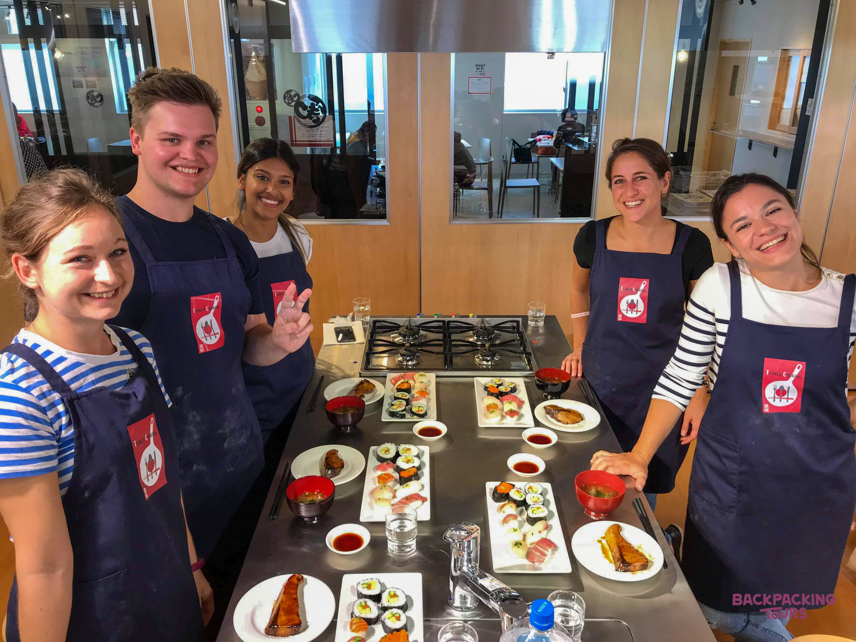 Five happy travelers proudly display their handmade sushi and miso soup at a cooking class in Tokyo.