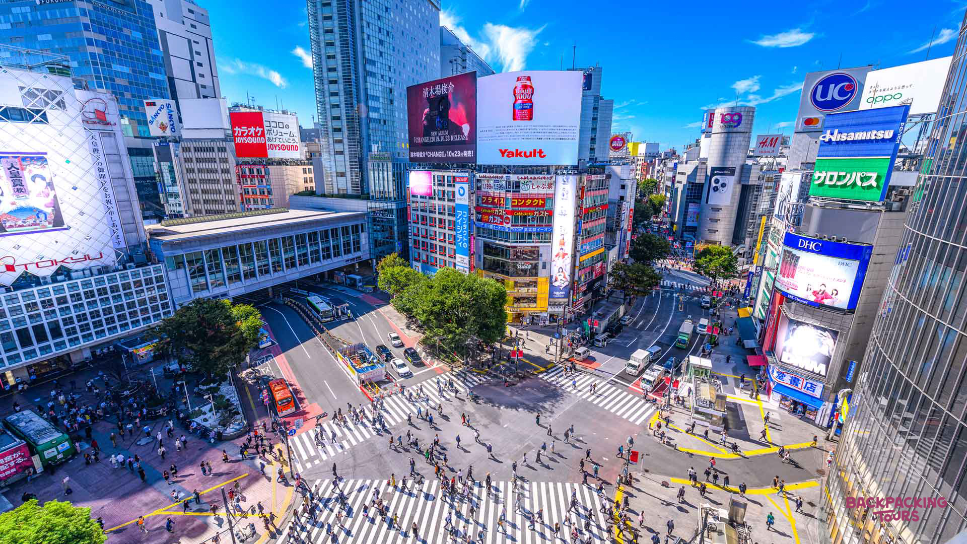 A bustling aerial view of Tokyo's famous Shibuya Crossing, with crowds of people navigating the street.