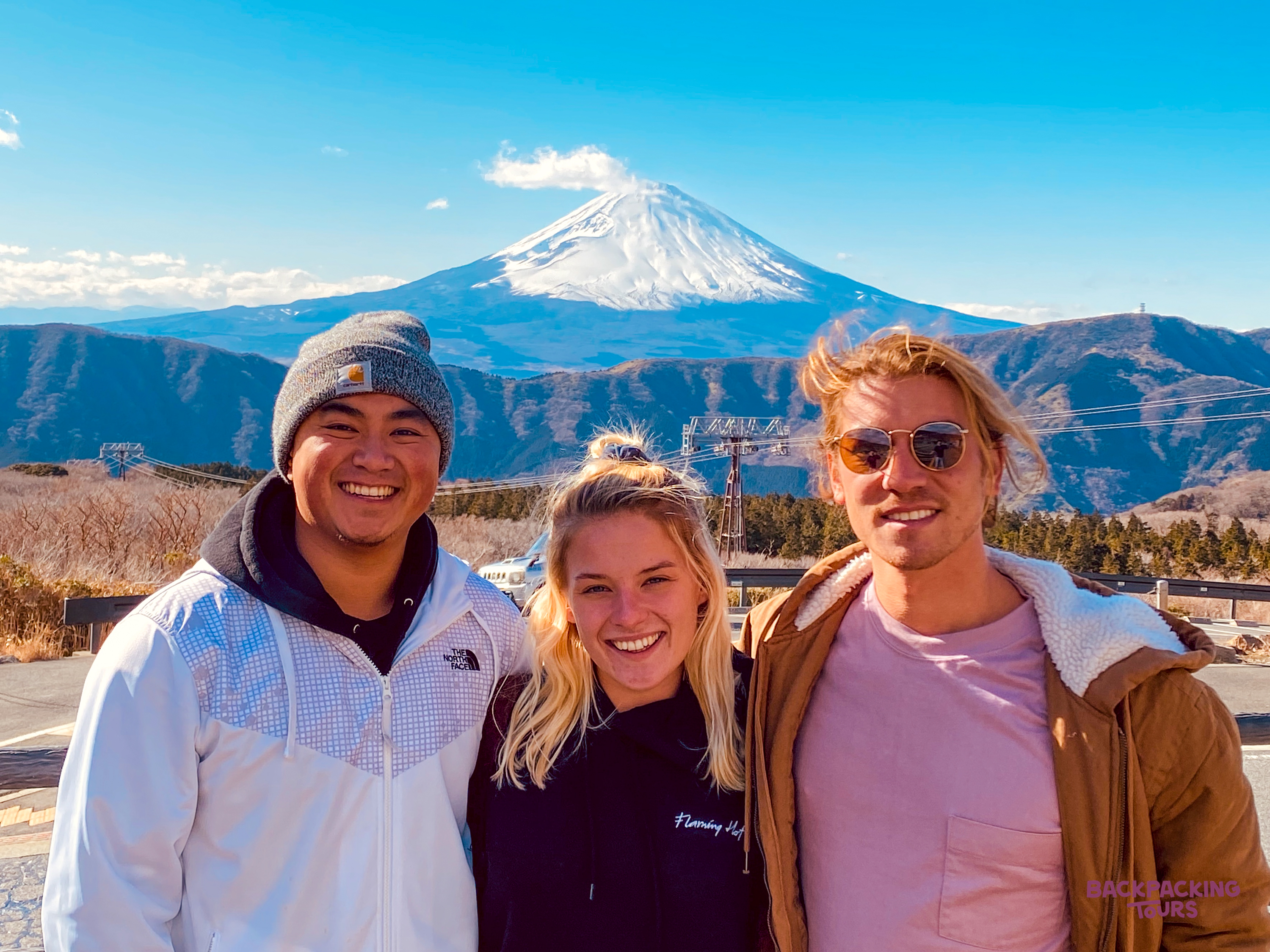 Smiling friends enjoy spectacular views of Mount Fuji on a sunny day in Hakone, Japan.