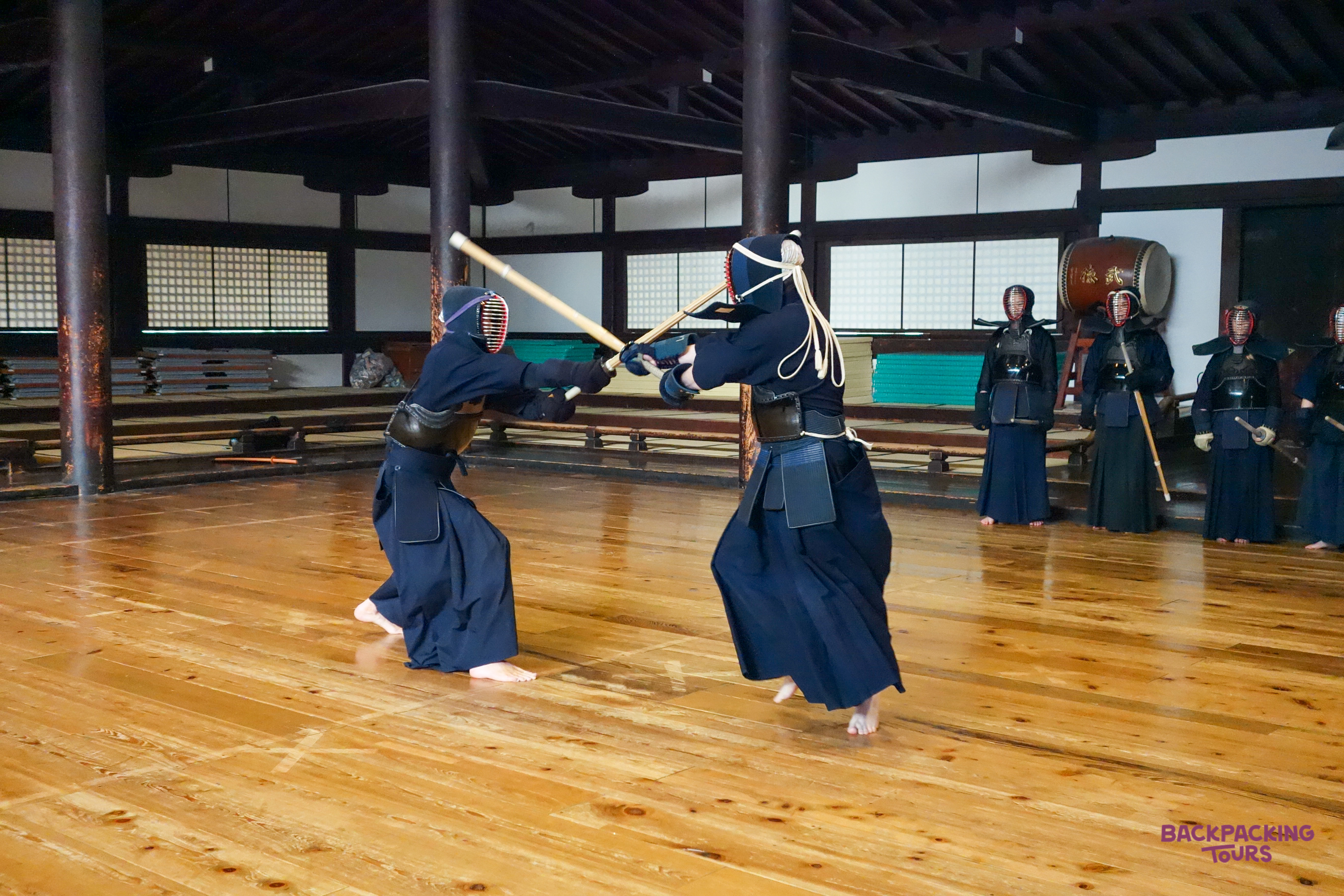 Two Kendo practitioners in traditional gear clash bamboo swords during a class in Kyoto.