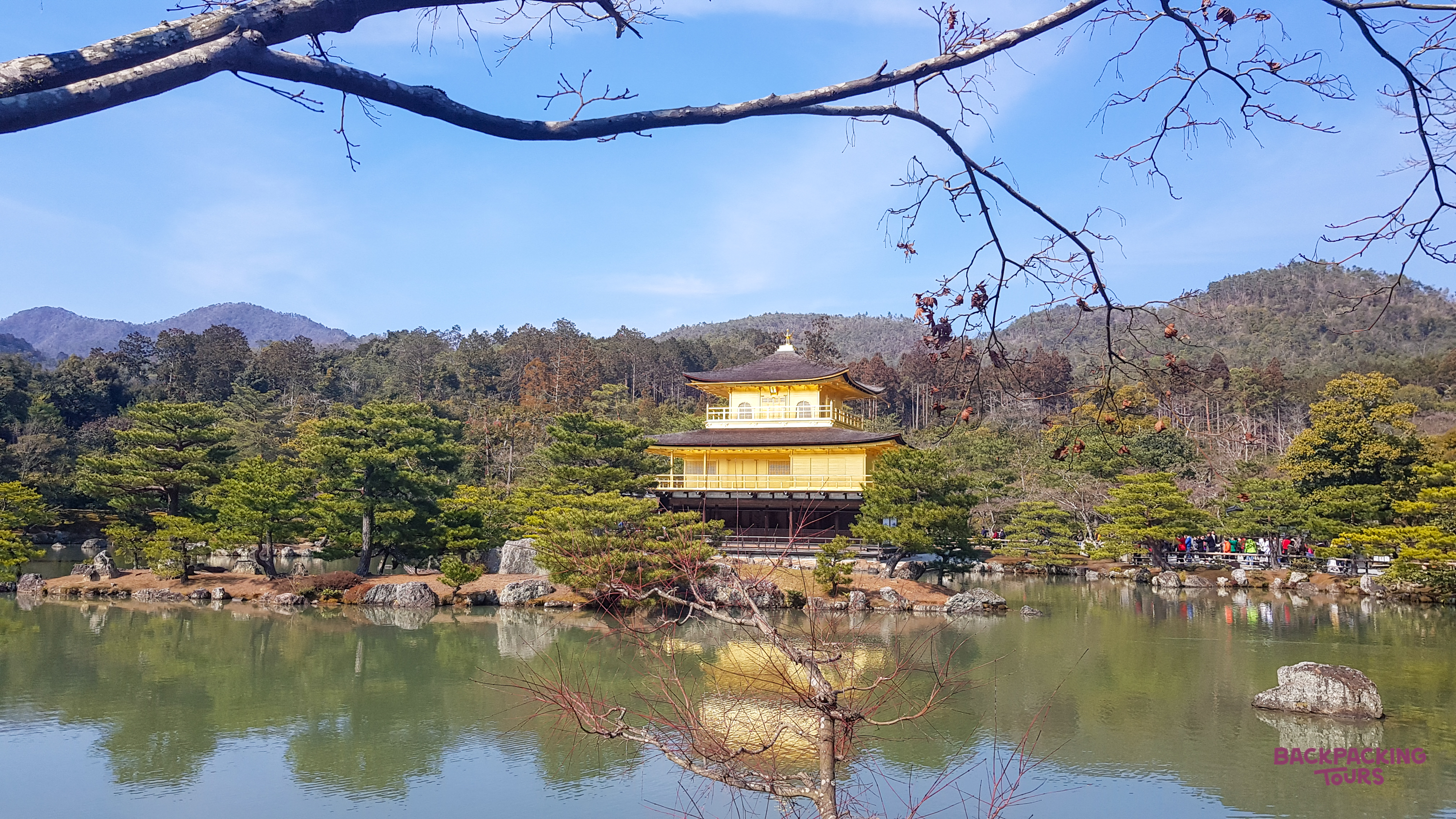 The iconic Golden Pavilion in Kyoto, Japan, reflected in its serene pond on a bright day.