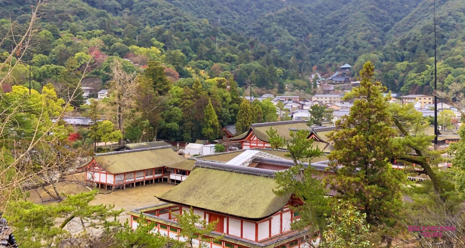 Traditional Japanese temple buildings with green roofs nestled among lush trees and mountains in Koyasan.