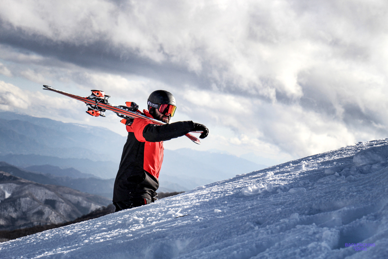 A skier carving down a snowy slope in the mountains near Nagano.