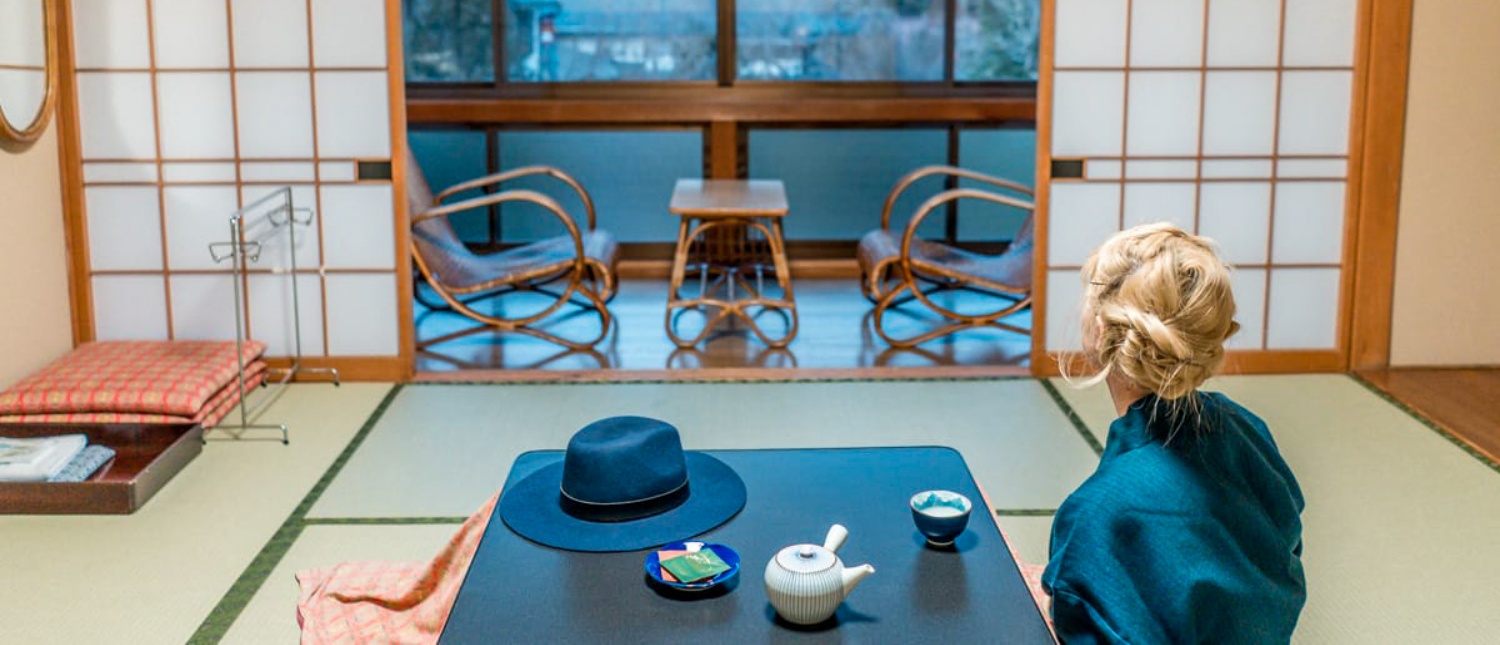 A traveler sits on tatami, enjoying tea in a traditional Japanese room at Koyasan.