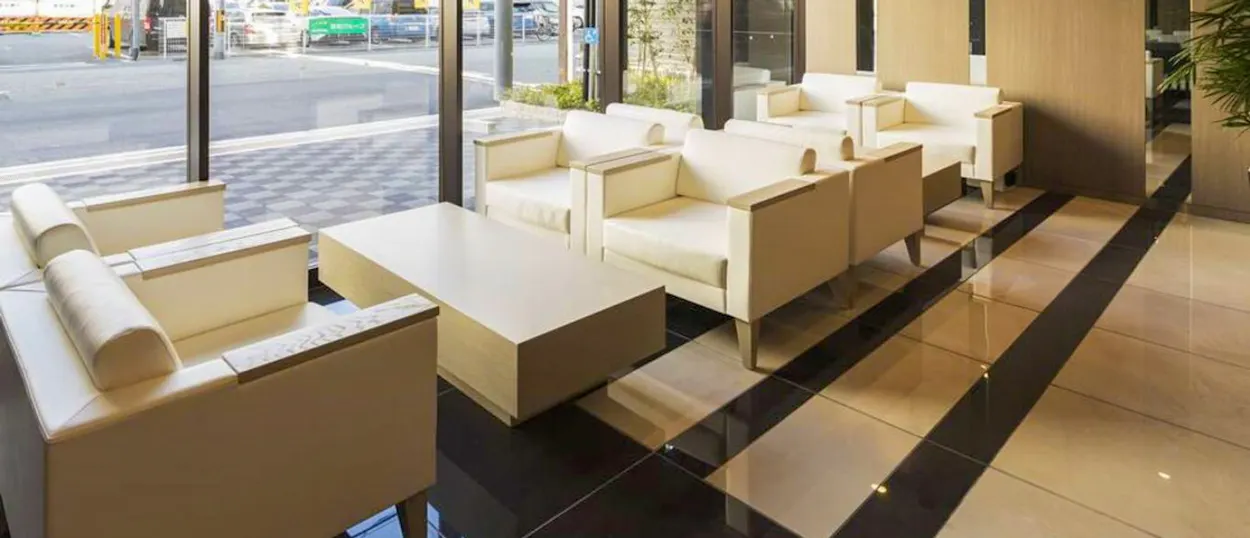 Modern hotel lobby in Osaka with light-colored armchairs, a coffee table, and large street-facing windows.