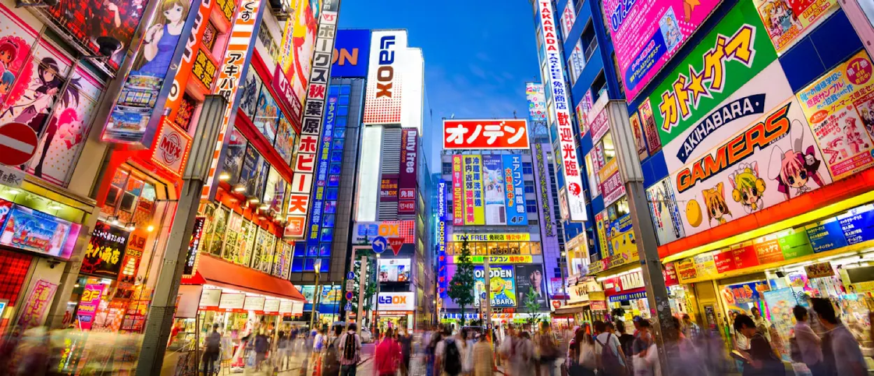 Bustling Akihabara street in Tokyo at night, illuminated by countless colorful neon signs and advertisements.