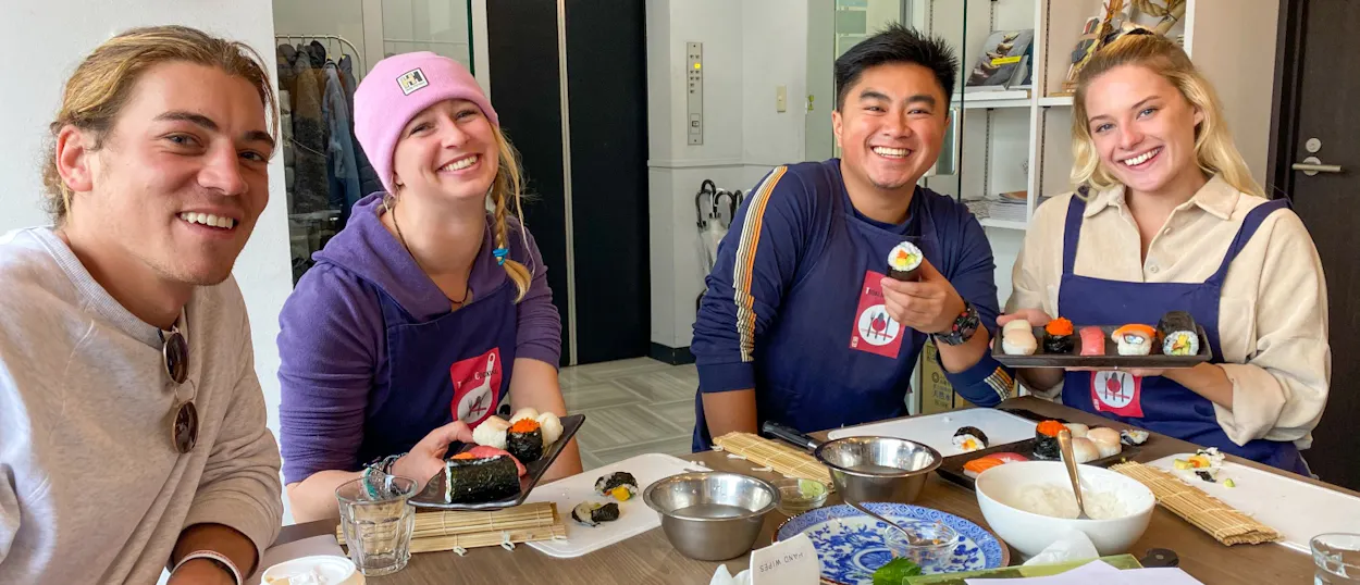 Four happy travelers learning to make sushi in a fun class in Tokyo.