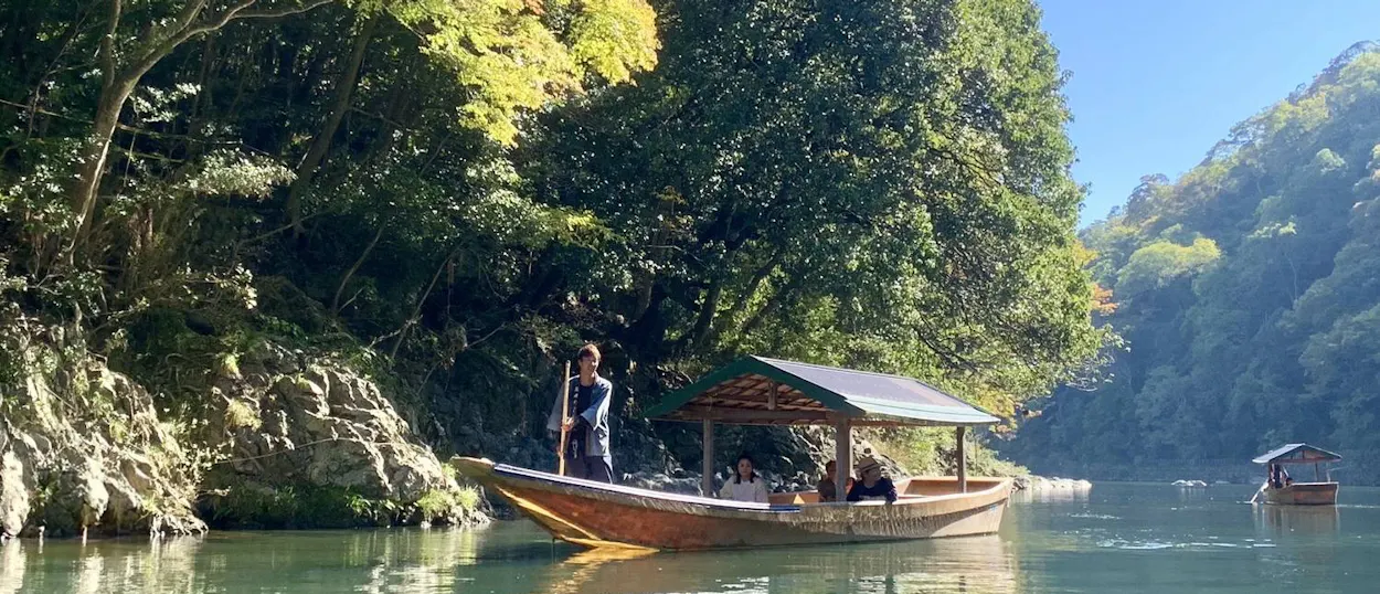 Passengers enjoy a traditional boat ride on a scenic river surrounded by lush green mountains in Hakone.
