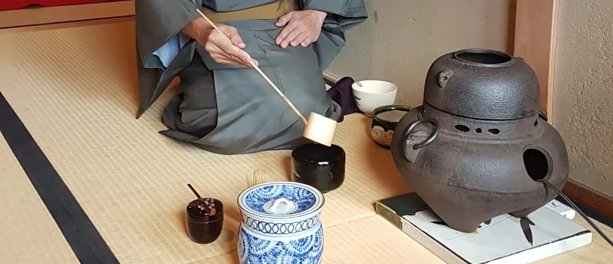 A person in traditional Japanese attire performs a tea ceremony on tatami mats in Kyoto.