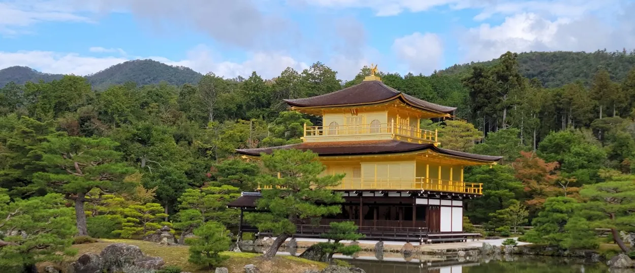 The Golden Pavilion in Kyoto, Japan, a shimmering gold temple reflected in a calm lake.