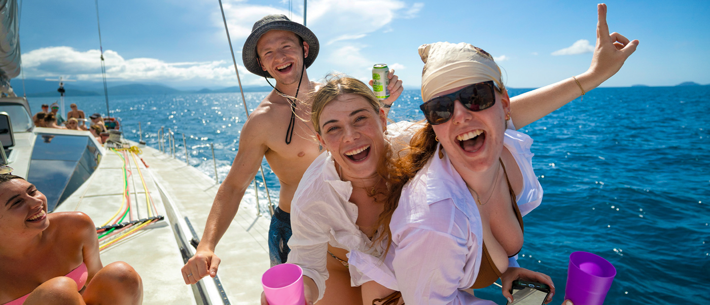 Joyful travelers dance and laugh on a boat in the beautiful Whitsundays, Australia.