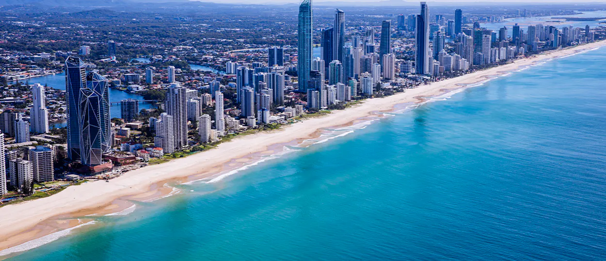 Surfers Paradise beach stretches along the Gold Coast with towering skyscrapers and clear blue water.