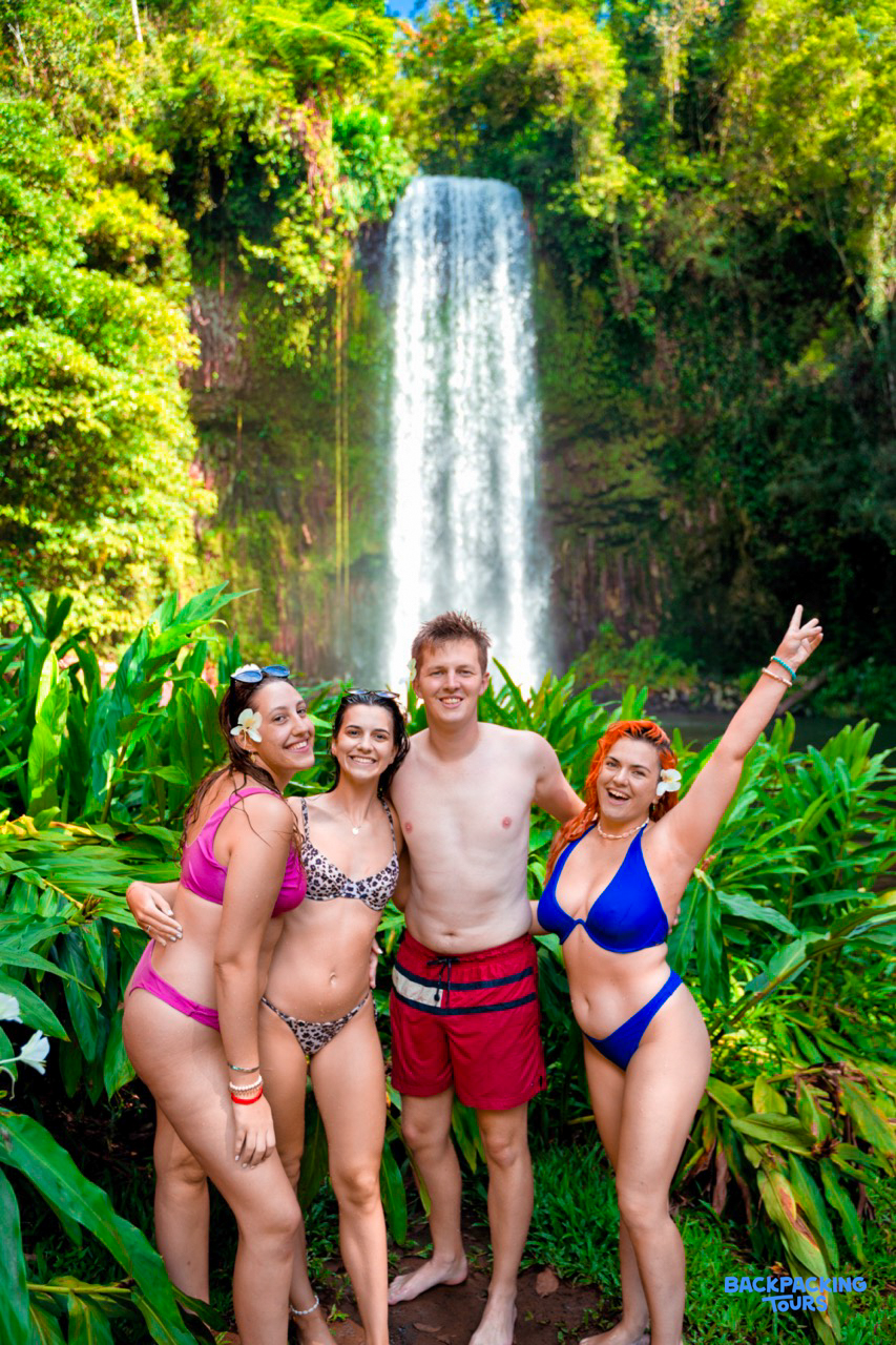 Happy backpackers pose in front of Millaa Millaa Falls in Australia's lush Atherton Tablelands.