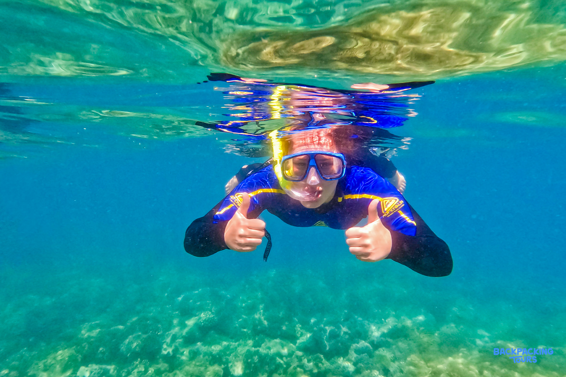 A happy snorkeller gives two thumbs up, enjoying the vibrant underwater world of the Whitsundays.